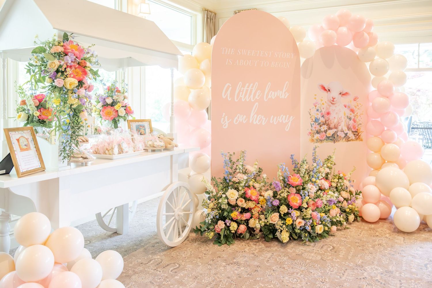 Elegant baby shower setup with peach and coral floral arrangements, balloons, and soft lighting creating a romantic atmosphere.