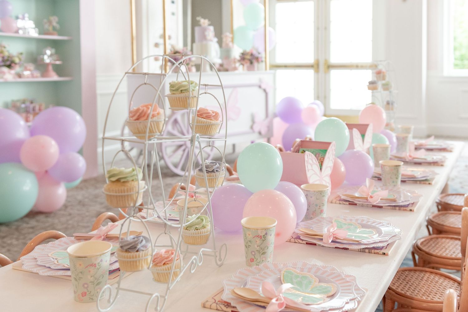 Pastel party table settings with balloons, floral centerpieces and vintage decor create a whimsical celebration atmosphere.