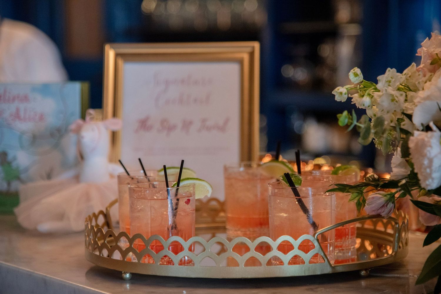 Baby Shower details featuring elegant gold frames, floral arrangements, and romantic candlelight decor on display tables.