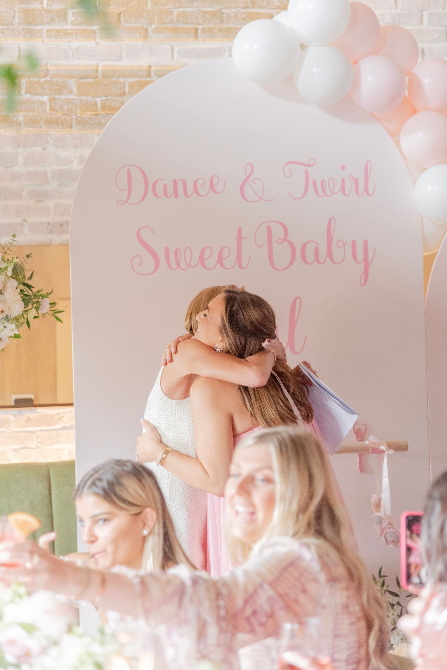 Guests enjoying a festive pink-themed celebration with dancing and socializing in a room with exposed brick walls.