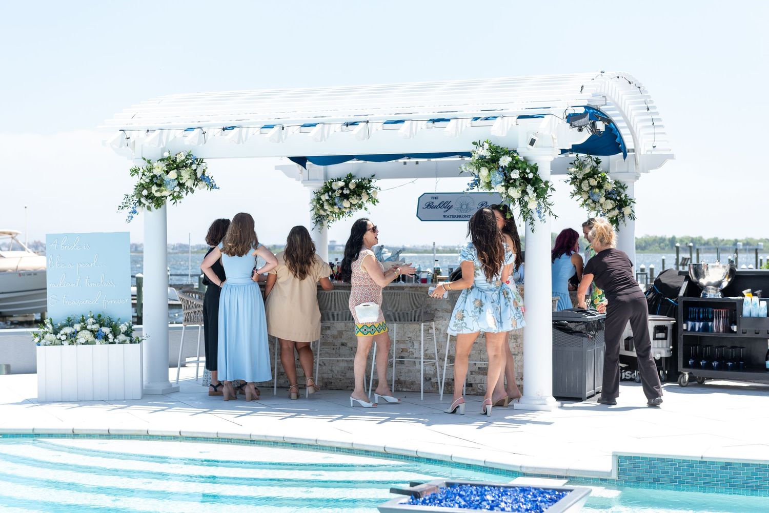 Guests enjoy signature cocktails at an outdoor bar at a bridal shower by the sea.