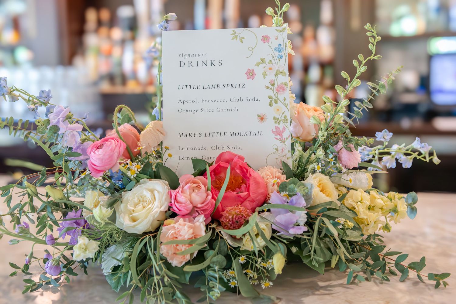Elegant floral centerpieces arranged on a rustic wooden surface for our custom drink menu.