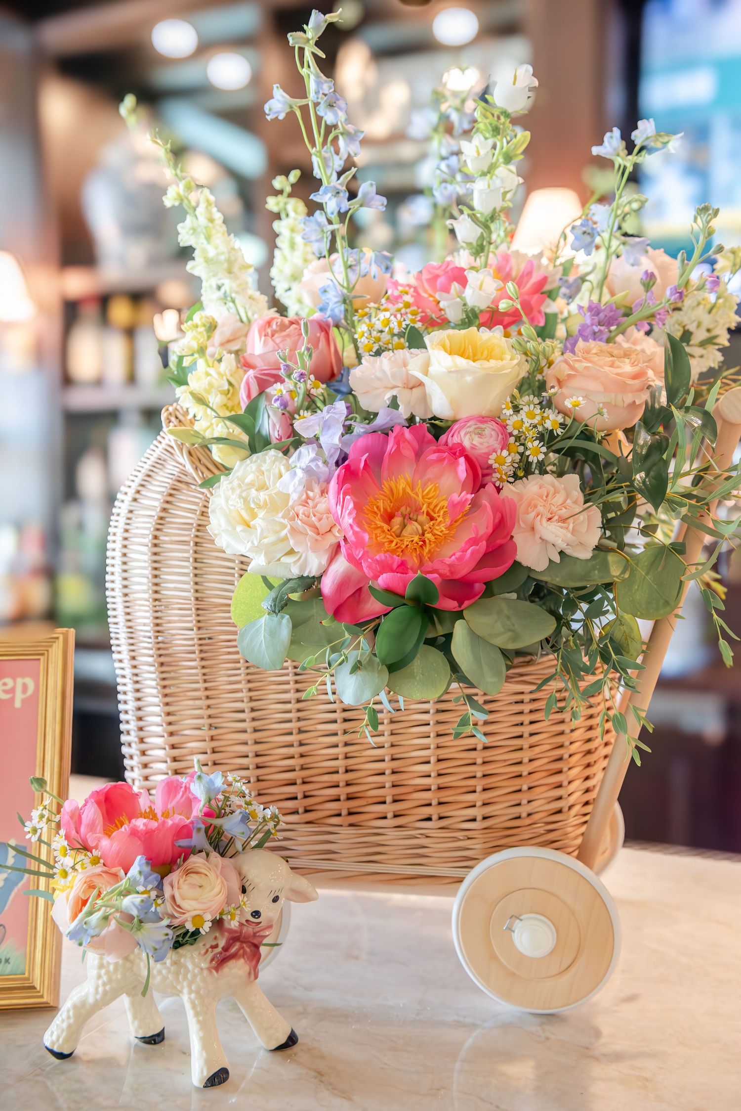 Wicker basket centerpiece with pink peonies, white flowers and eucalyptus arranged for a special event.