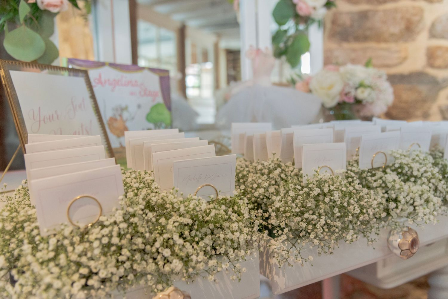 Baby shower escort cards displayed on delicate baby's breath flowers create an elegant seating arrangement display.