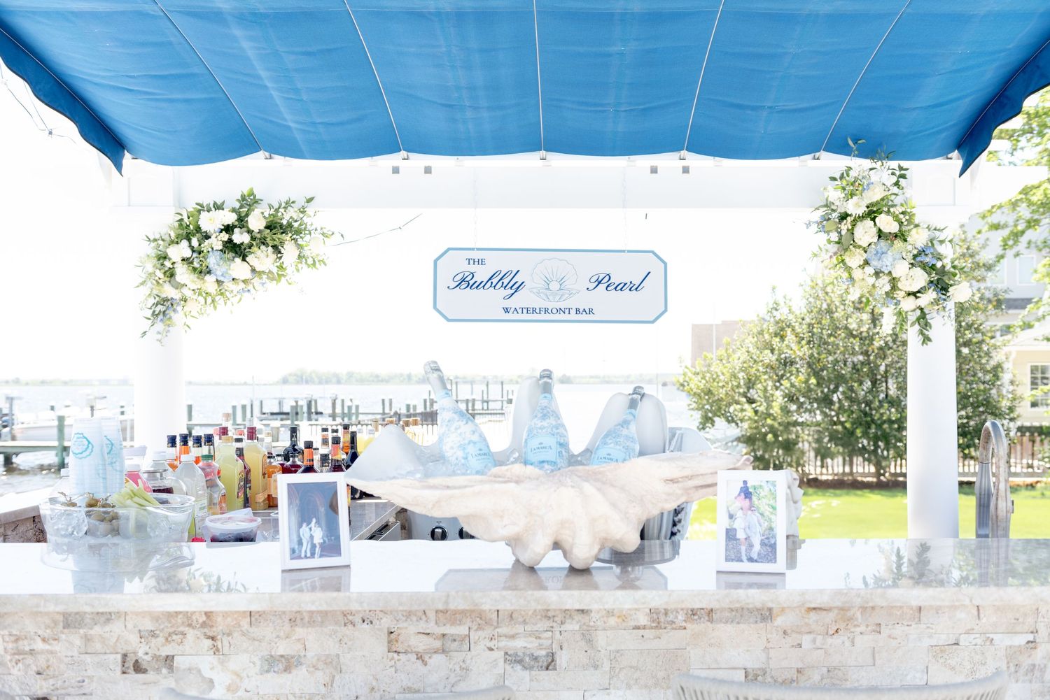 A white and blue outdoor wedding reception setup with tables and chairs arranged under a tent canopy.