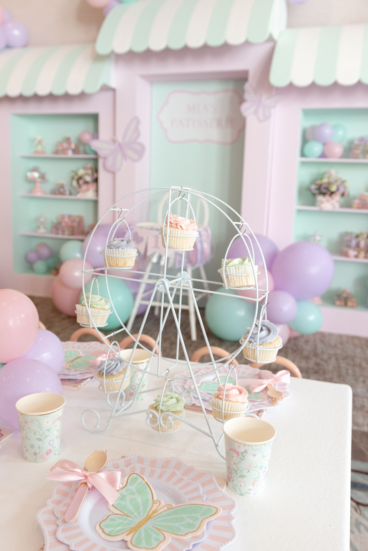 Pastel mint and lavender party decor with butterfly motifs and delicate wire displays in a shabby chic setting.