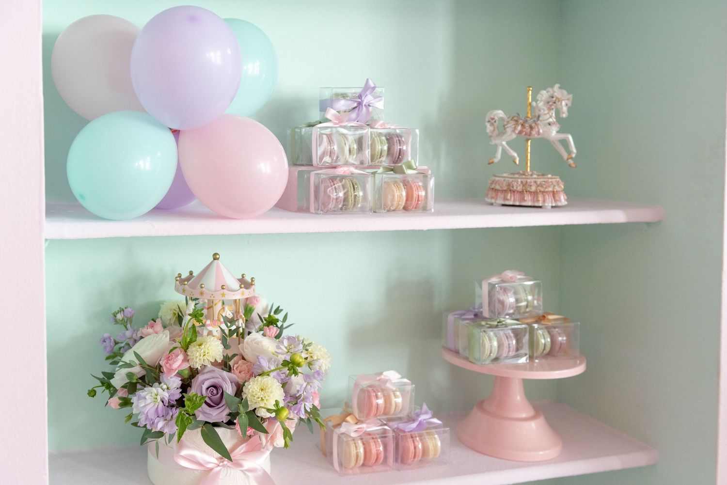 Pink and white party decorations with balloons, floral arrangements, and tiered cake stands create a dreamy dessert display.