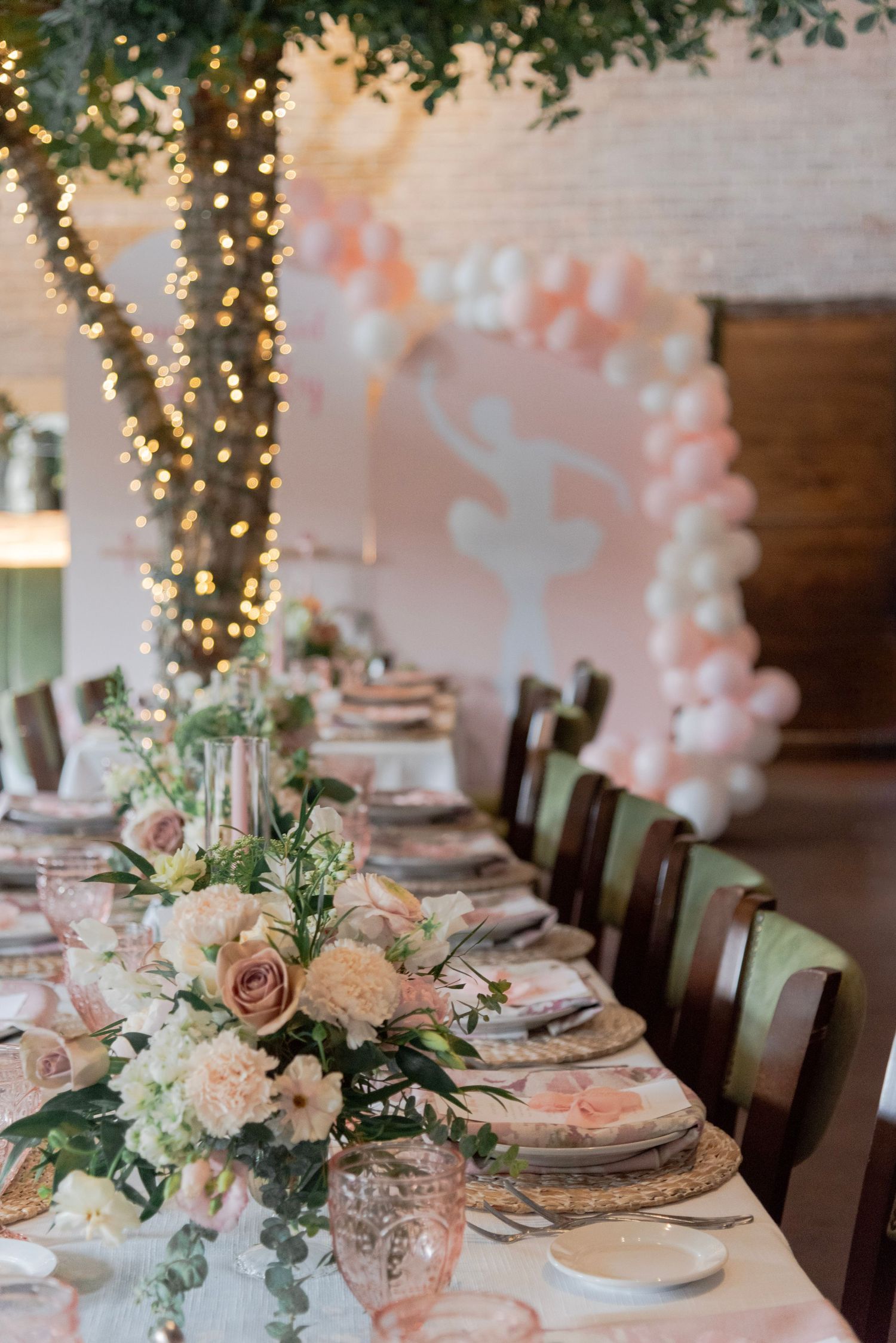 Elegant table settings with pink and white floral centerpieces, twinkle lights, and rustic decor for a romantic celebration.
