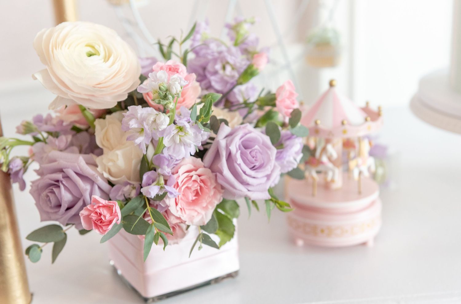 Soft pastel floral arrangements with roses and ranunculus in pink and lavender tones create a romantic wedding tablescape.