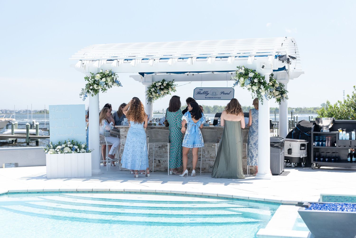 Guests order specialty cocktails at an outdoor bar at a bridal shower.