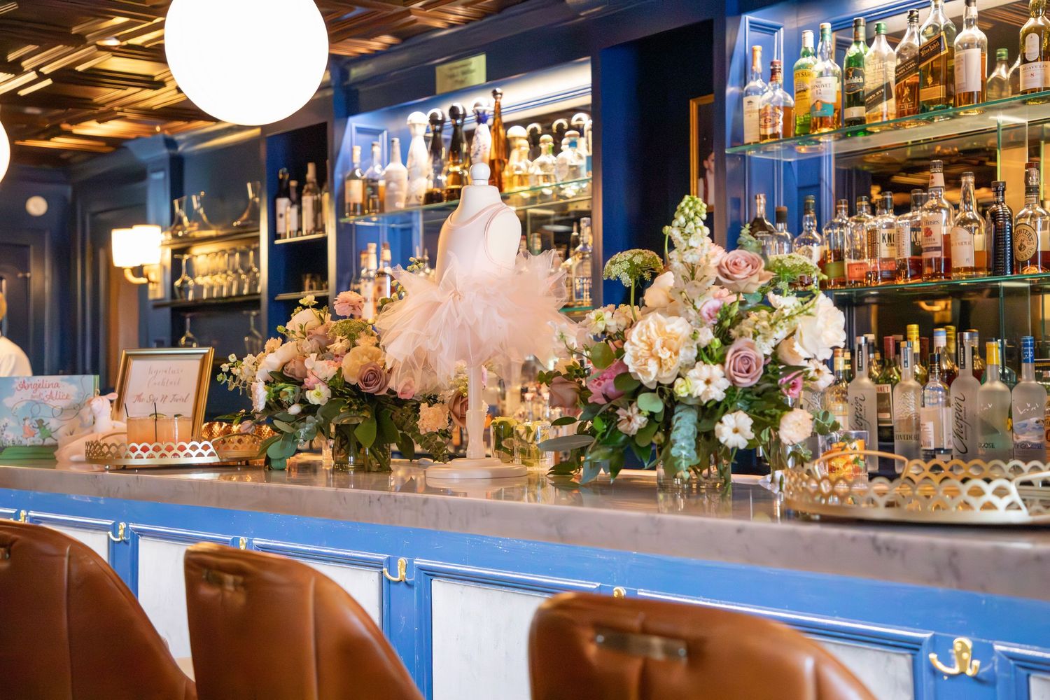 Elegant baby shower venue with blue lighting, white floral arrangements, and crystal chandeliers creating a romantic ambiance.