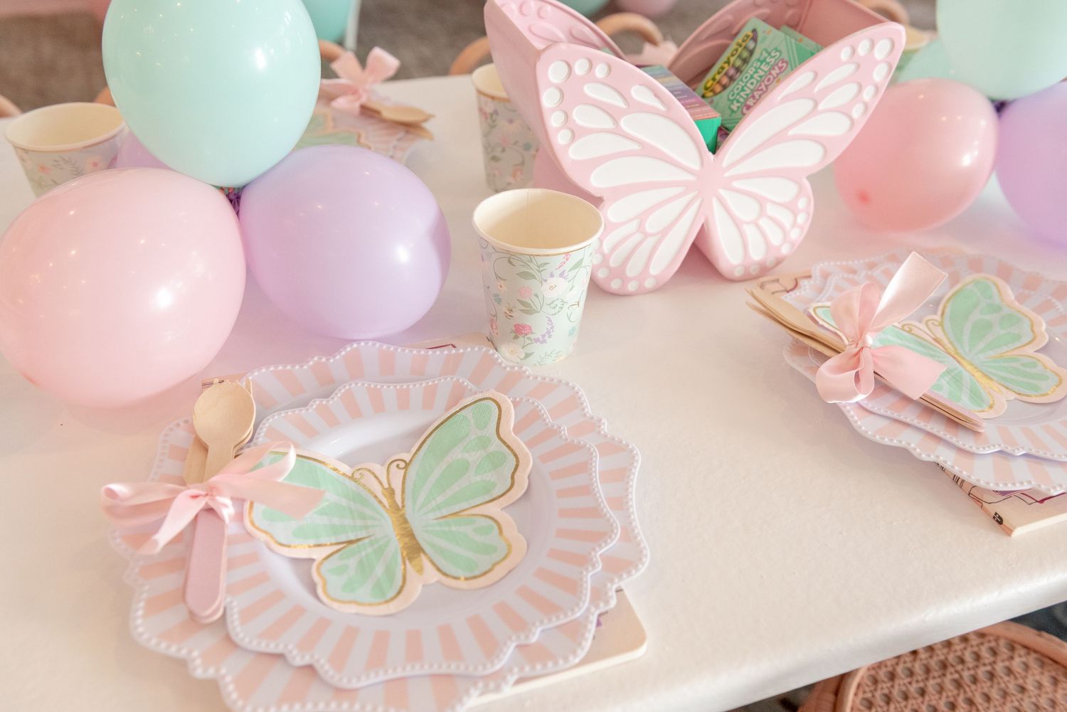 Pastel pink and mint green party decorations featuring delicate butterflies and balloons create a whimsical atmosphere.