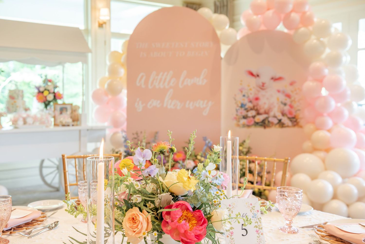 Elegant pink and white baby shower decorations with floral arrangements and balloon arches create a dreamy celebration space.