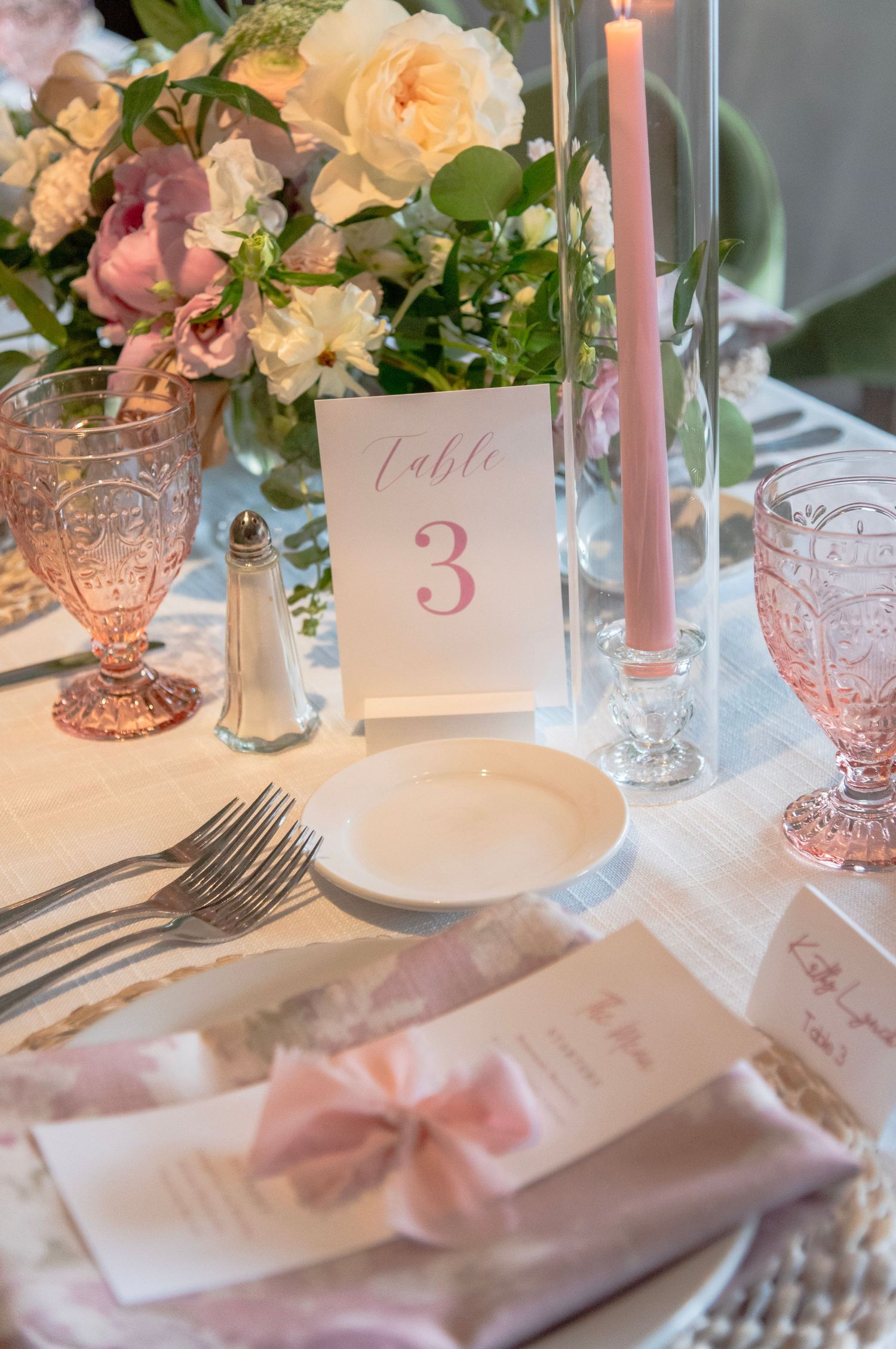 Elegant table setting with pink candles, floral centerpieces, and vintage glassware featuring table number three.
