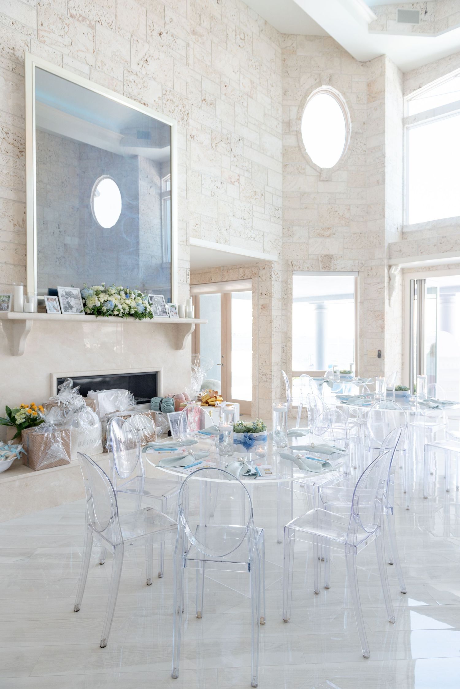 Modern event space with clear ghost chairs and exposed brick walls features elegant minimalist decor and natural lighting.