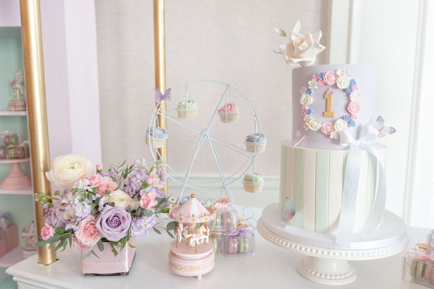 Pastel carousel themed party decorations with pink and gold accents displayed on a white dessert table.
