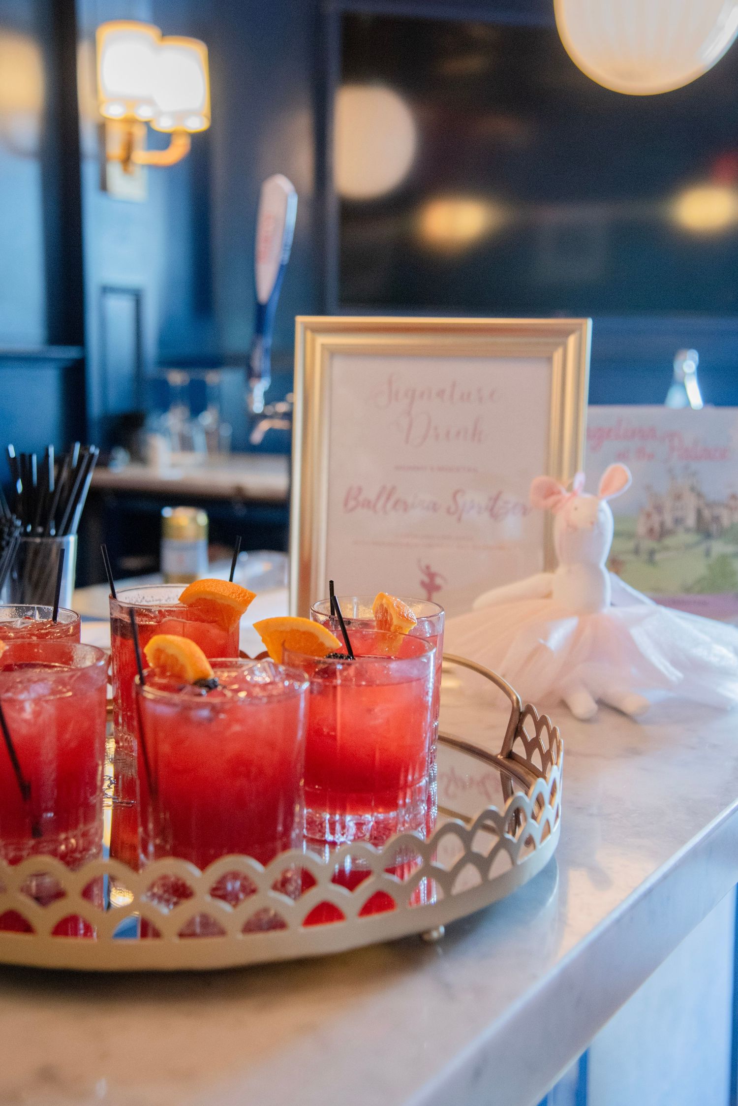 Red cocktails garnished with orange slices and berries are displayed on a white table at an event.