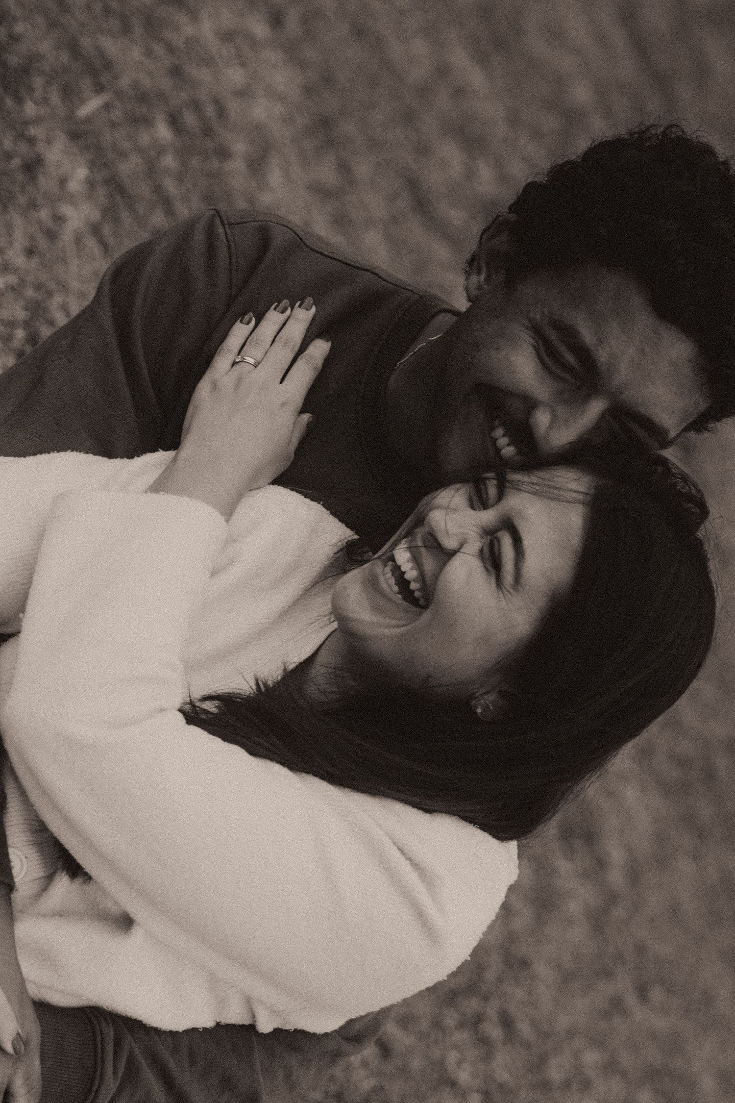 Black and white photo series of a person in a white sweater laying down and smiling expressively in various poses.