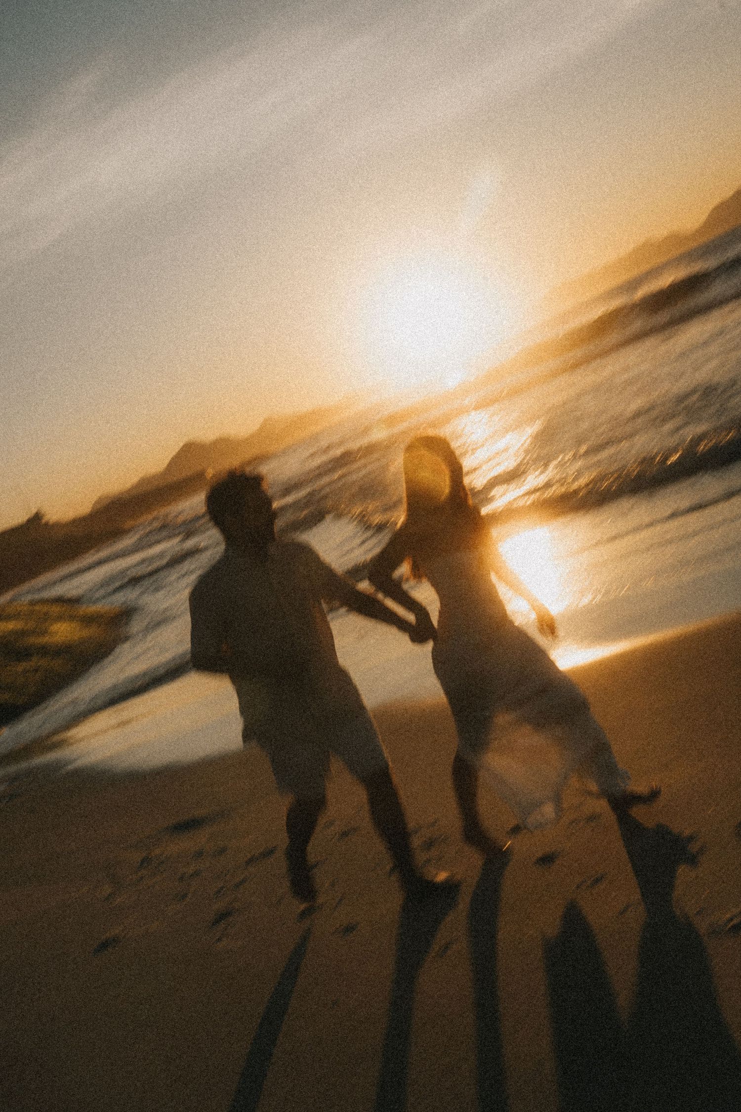 Silhouettes play and dance on a beach at sunset as golden light reflects off the ocean waves.