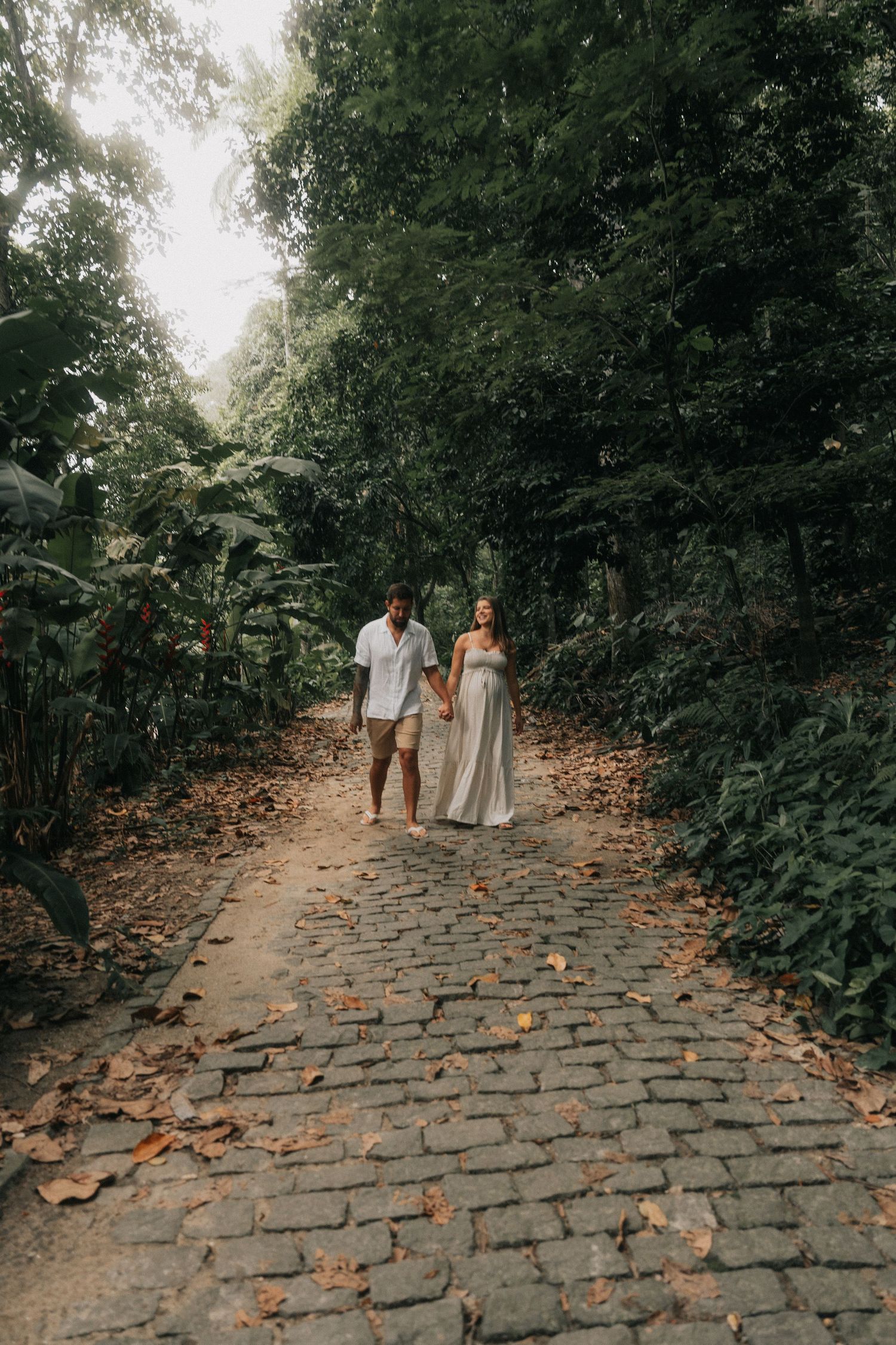 A couple walking together on a cobblestone path surrounded by lush greenery.