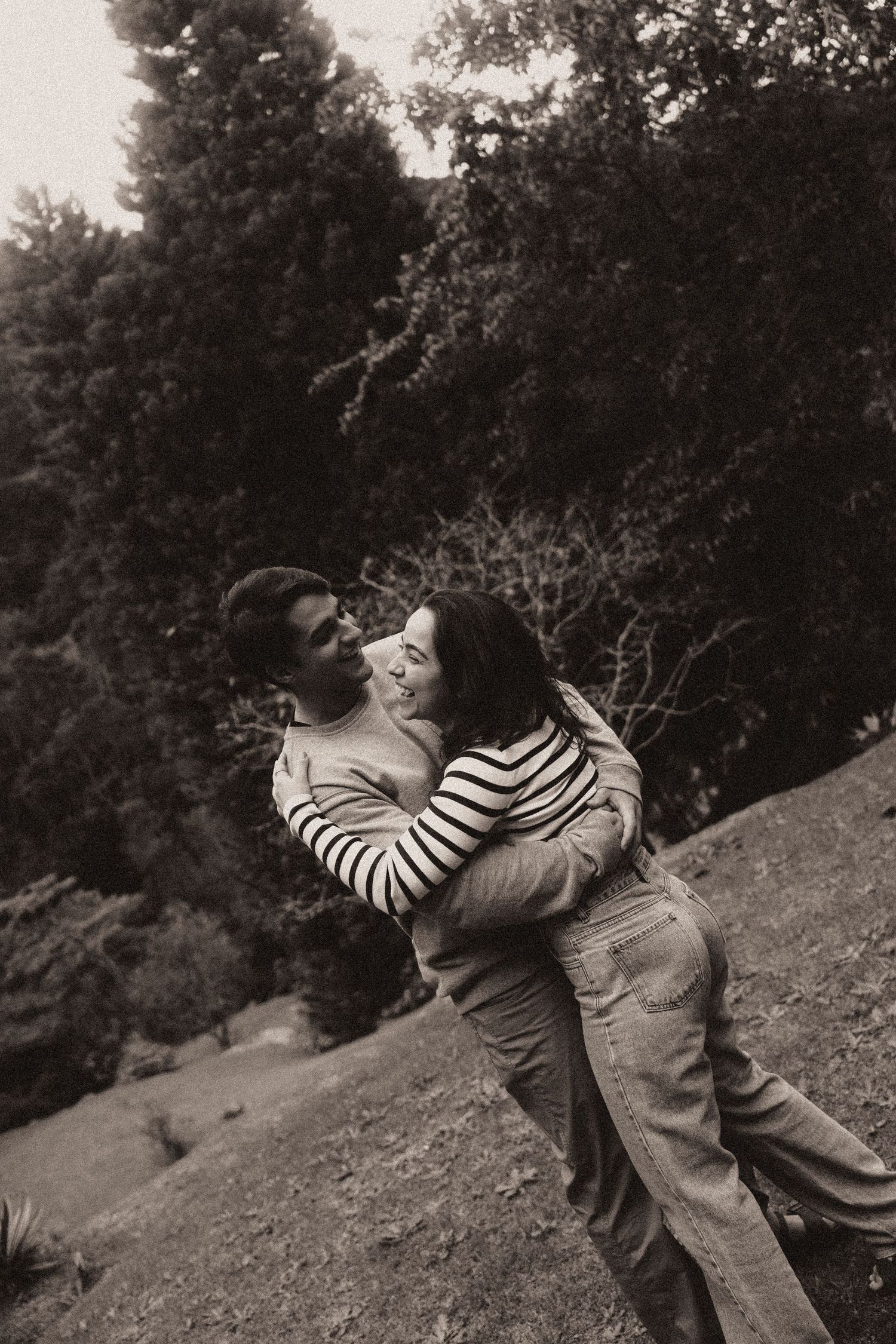 A couple embraces on a grassy hillside in a romantic black and white photo sequence.