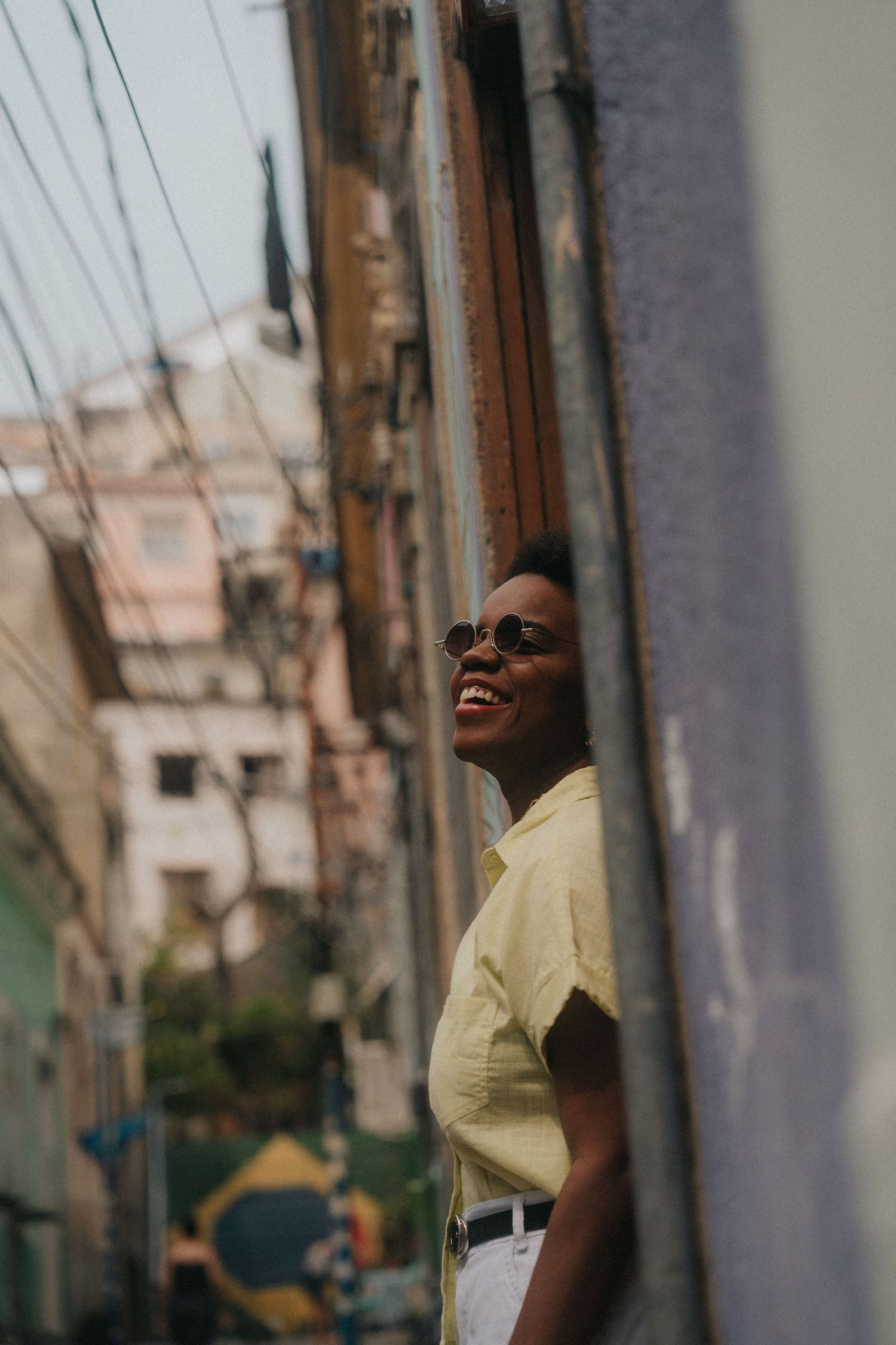 A sequence of four photos showing a person in a yellow shirt laughing joyfully against an urban backdrop.