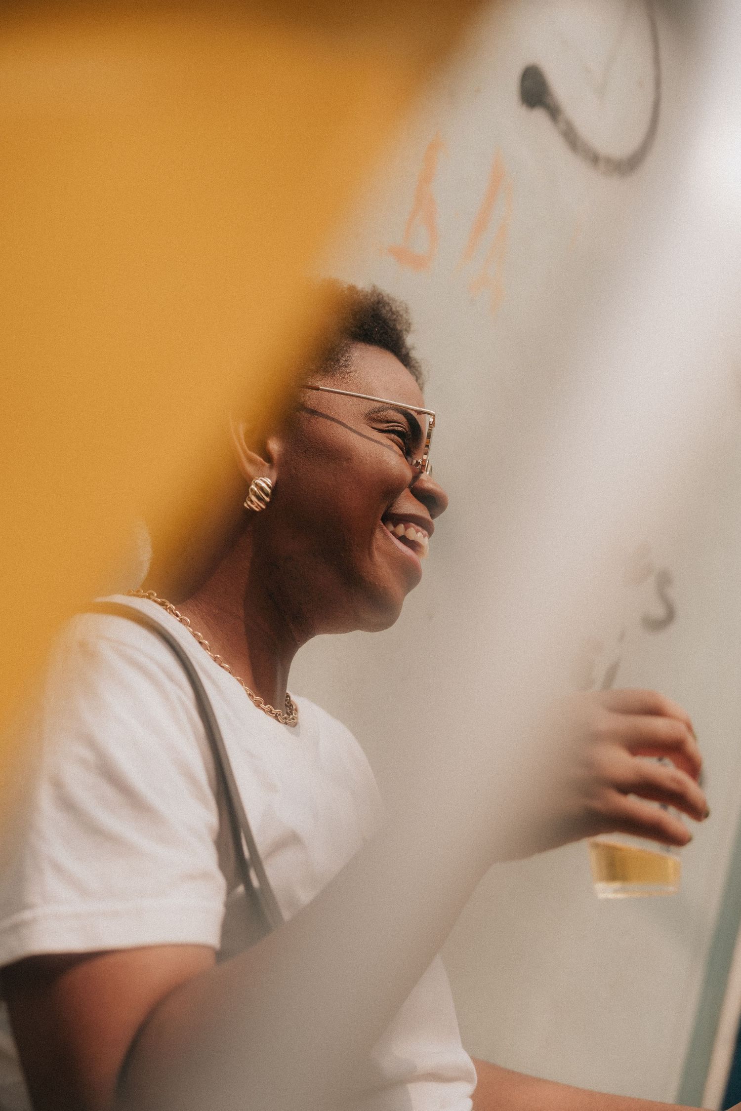 A person in a white t-shirt laughs joyfully in a sequence of candid photos with warm lighting and blurred edges.