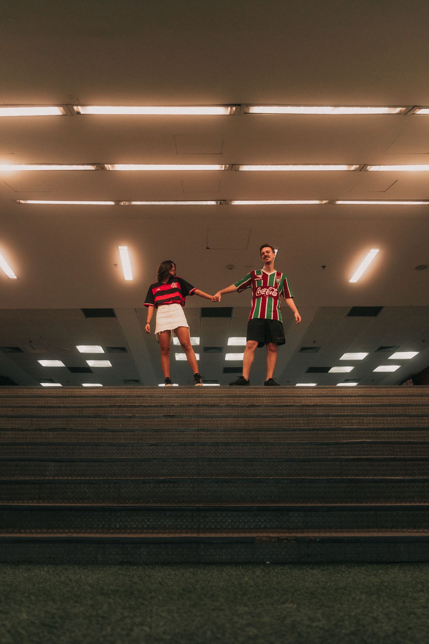 Athletes train on a stadium bleachers at dusk under fluorescent lighting.