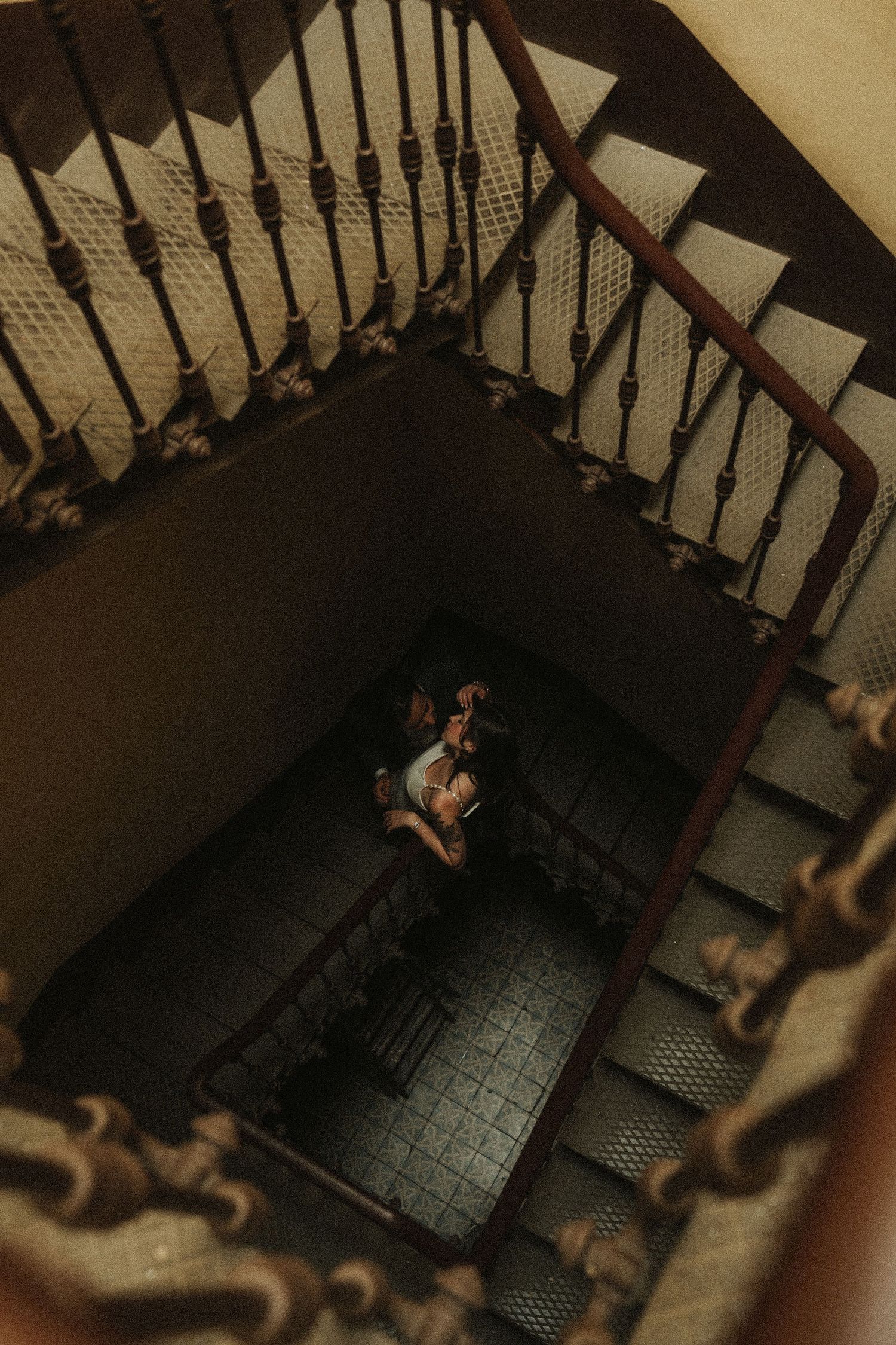 A sequence of dark stairwell photos showing a descending perspective with wooden railings and dim lighting.