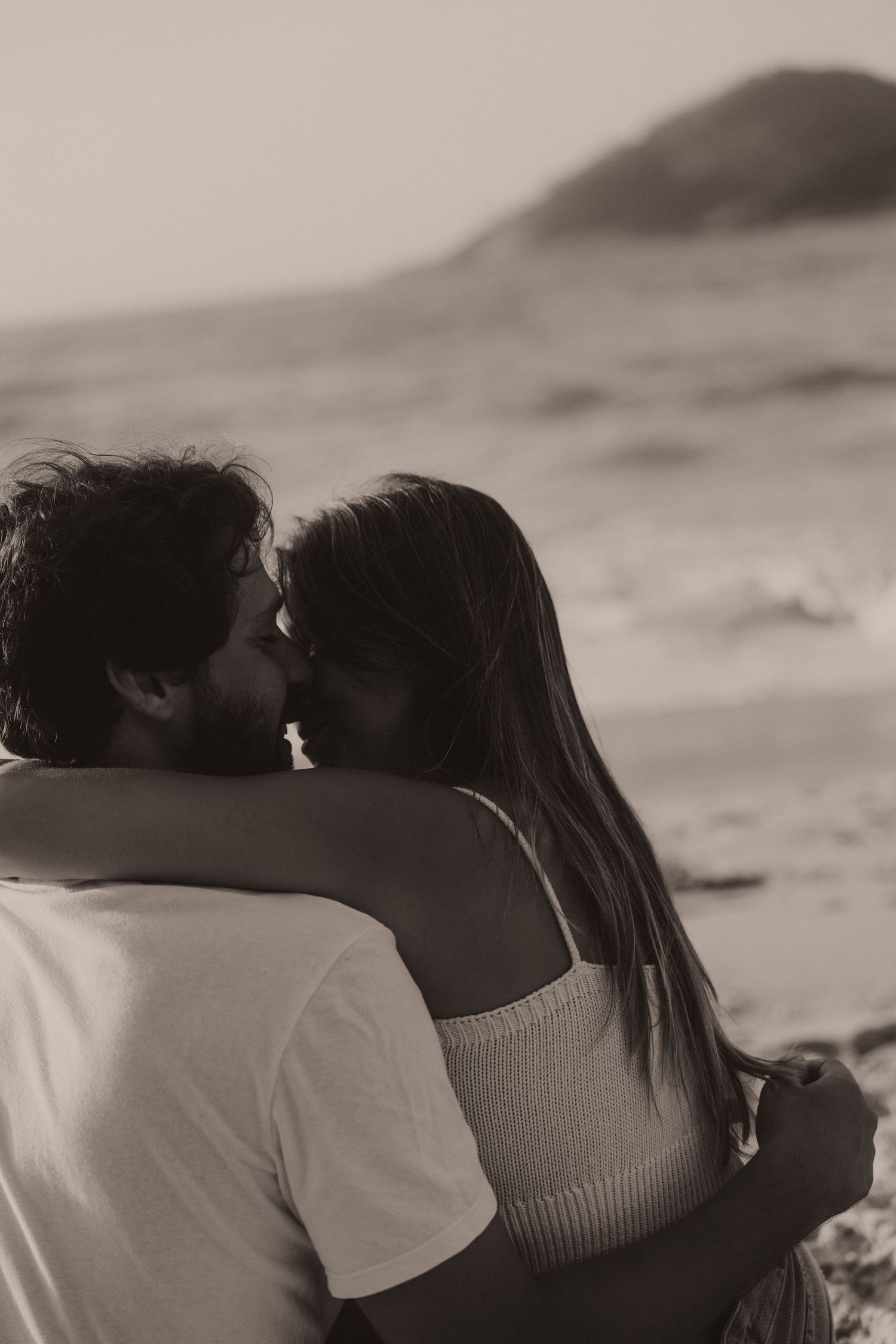 A black and white artistic photo series shows a romantic couple embracing on a beach.