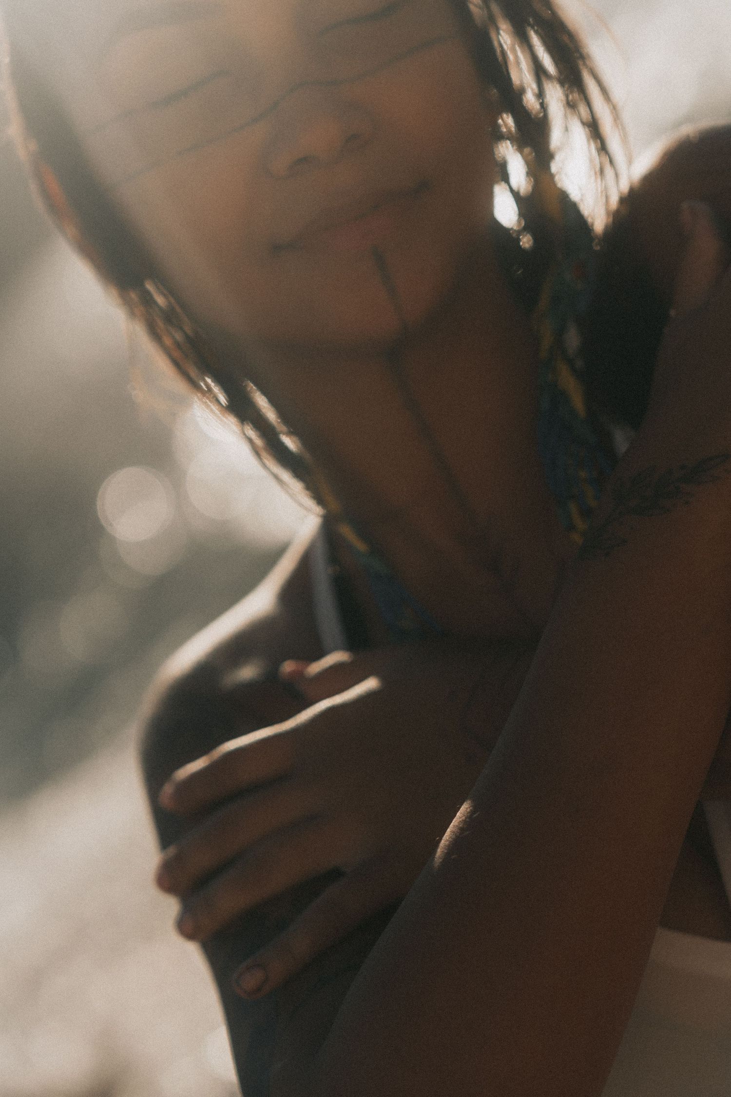 Artistic close-up portrait in sepia tones showing profile silhouette and neck against blurred bokeh background.