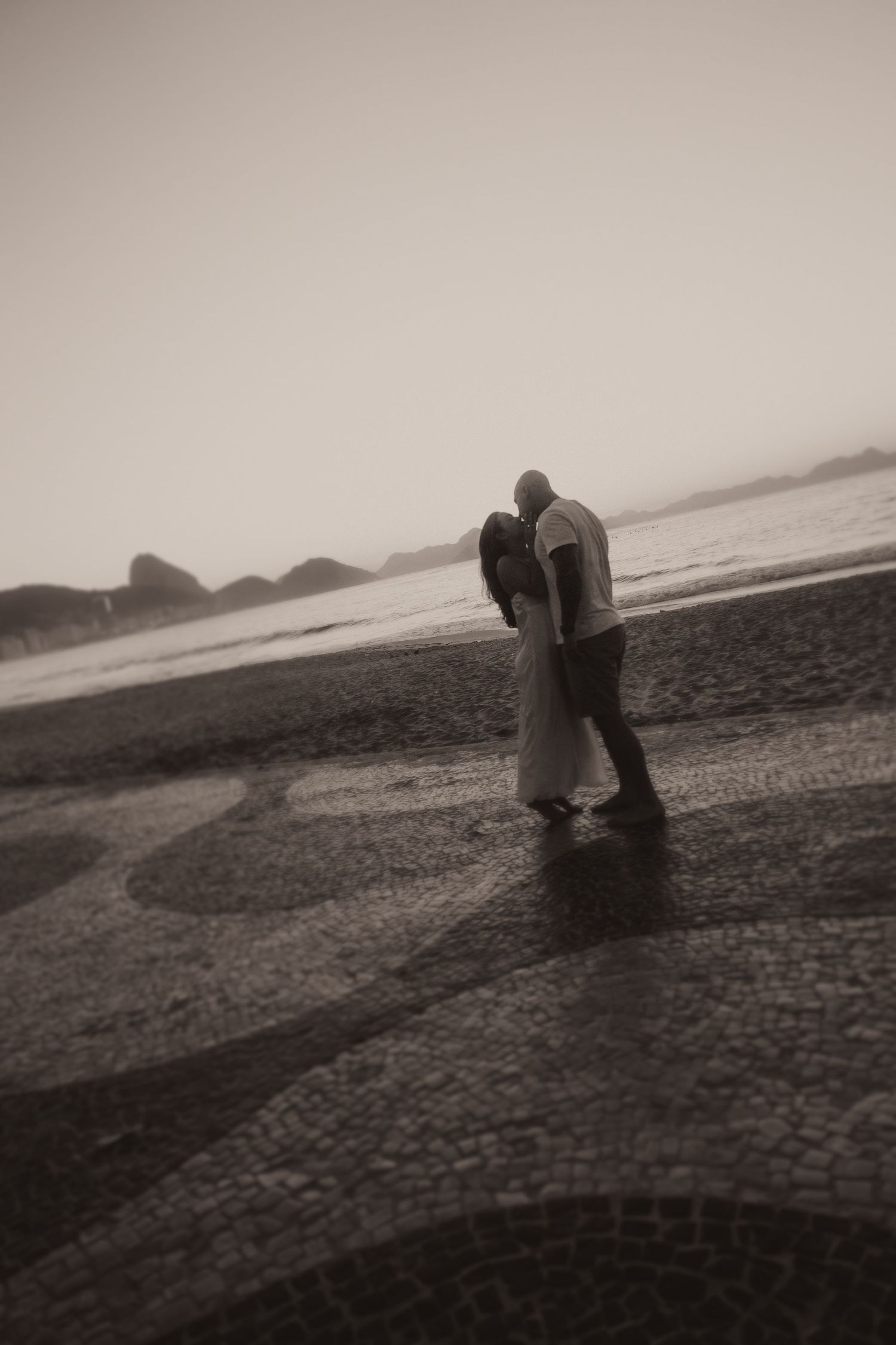 A sequence of black and white photographs shows a solitary figure bending down in a misty field against an overcast horizon.