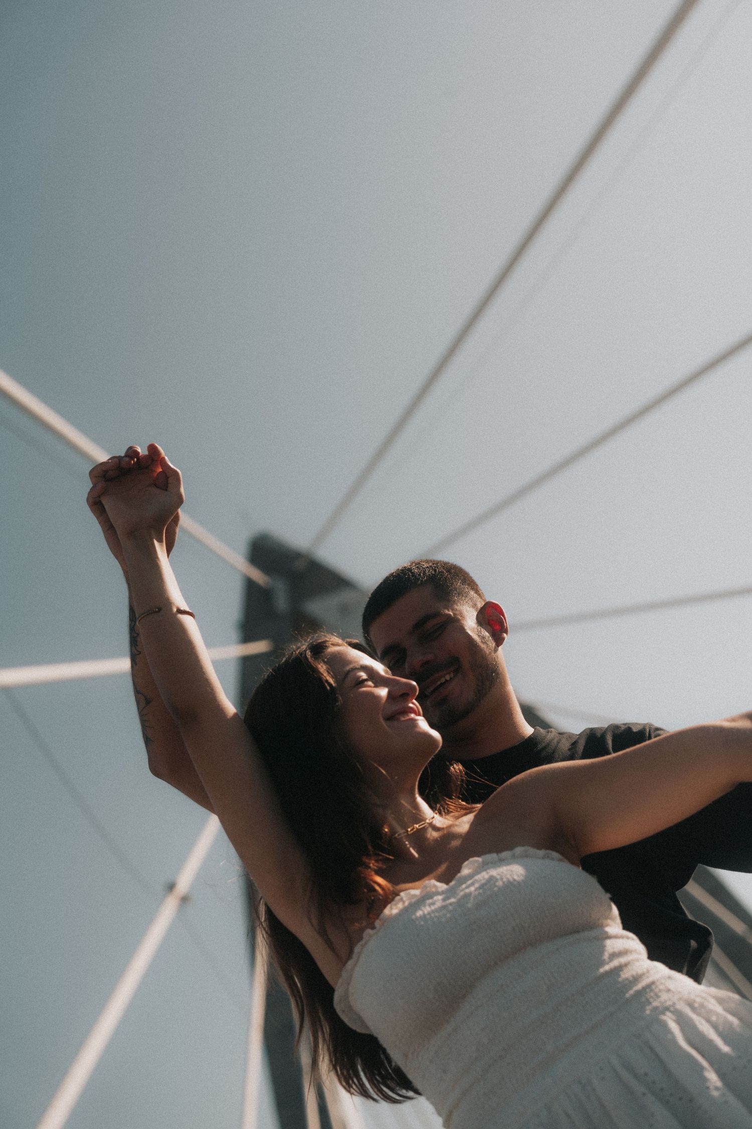 Couple dancing and embracing in a white and sunlit room under slanted ceiling beams create a romantic moment.