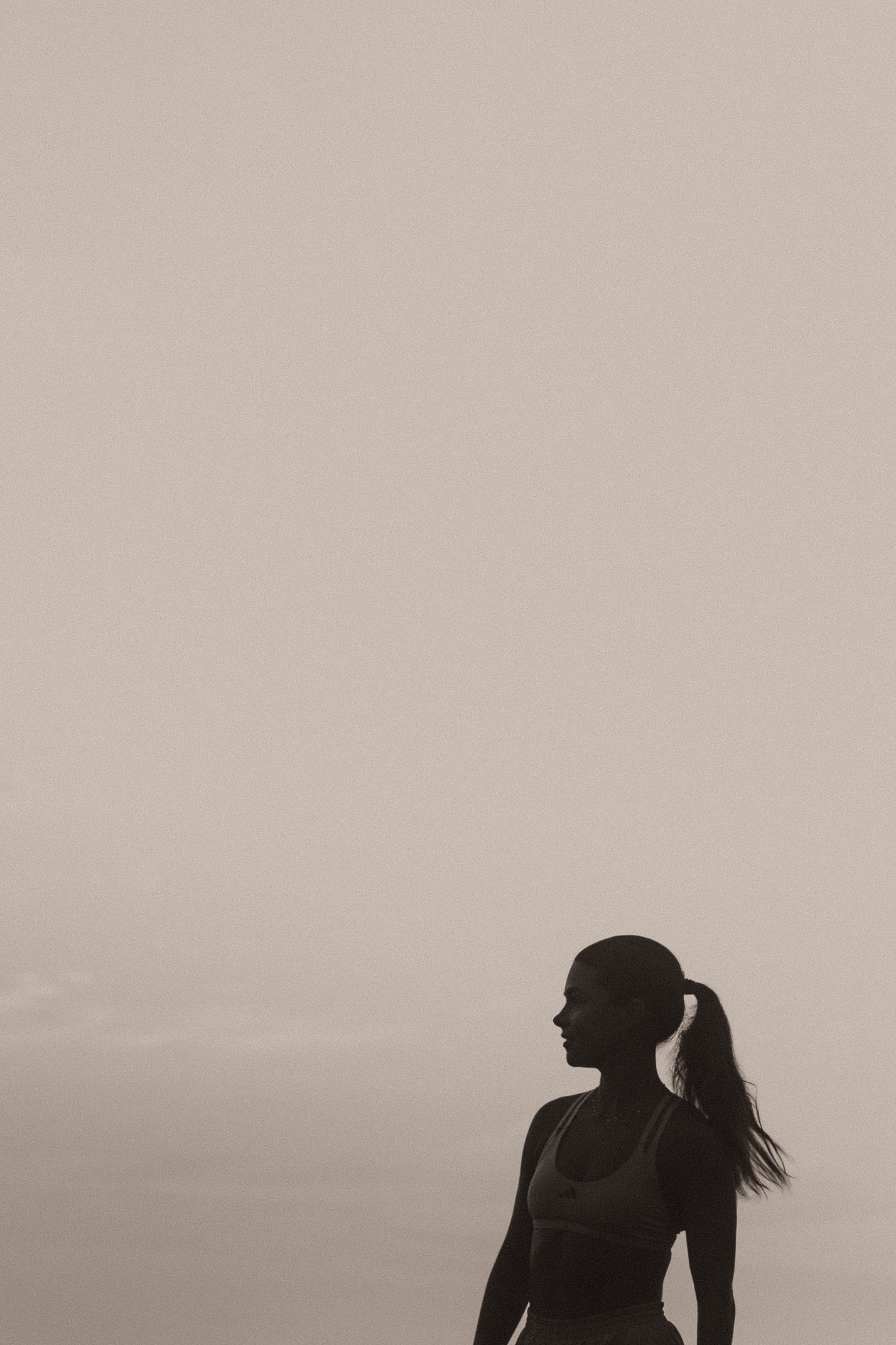 Silhouetted figures stand together in a romantic pose against a misty gray background creating a dreamy atmosphere.