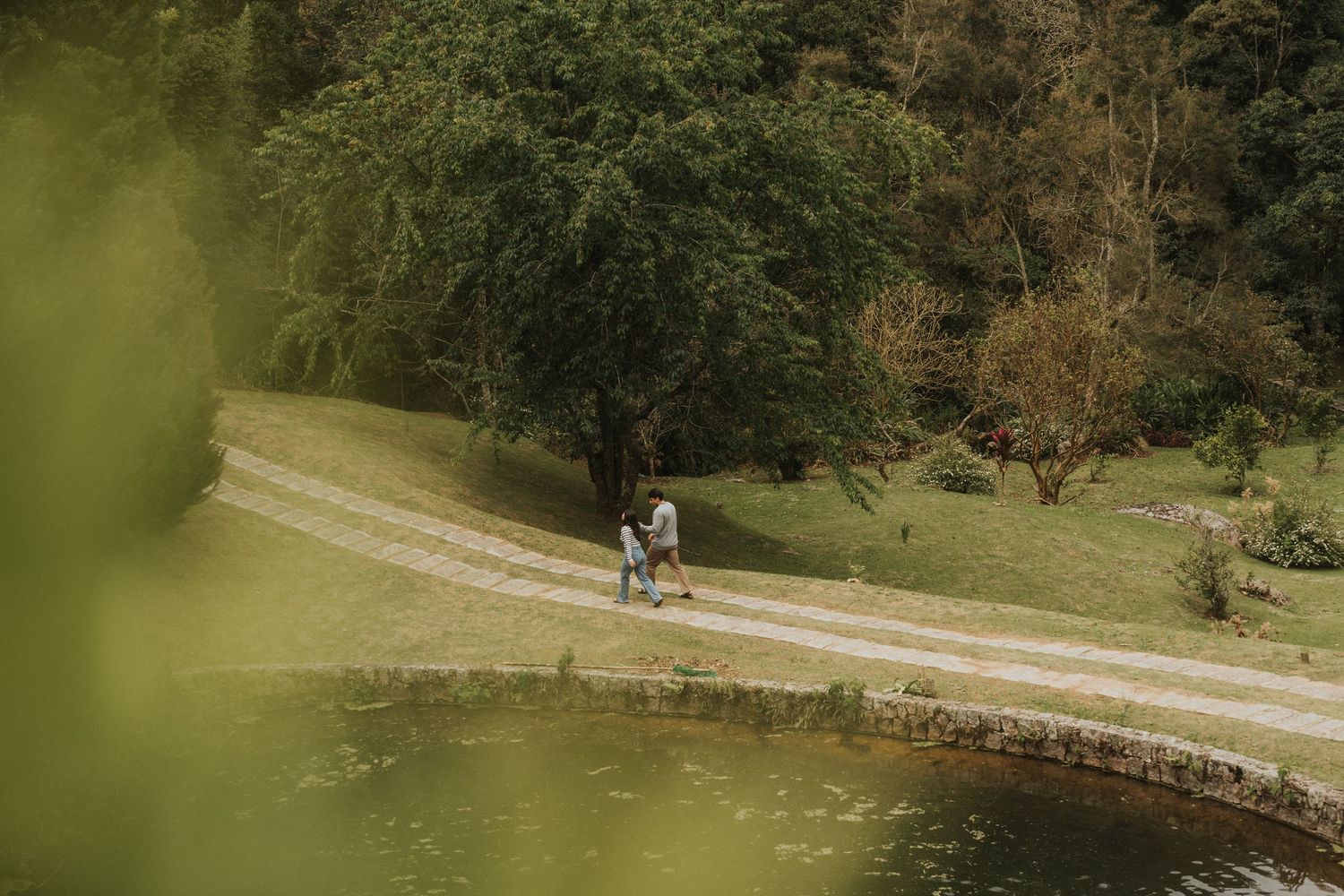 A couple walks along a winding gravel path through a scenic park on an autumn afternoon.