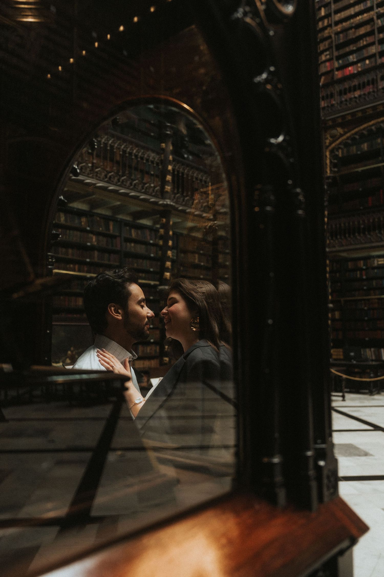A couple shares an intimate moment in a dark wine cellar with wooden wine racks in the background.