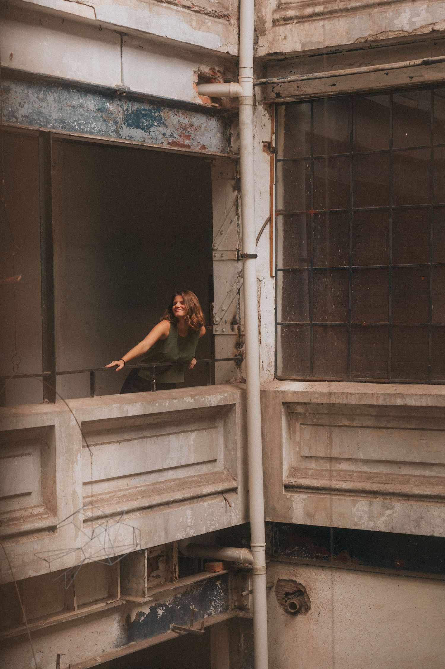 A dark and abandoned interior space of an old building with curved concrete architectural elements and peeling walls.
