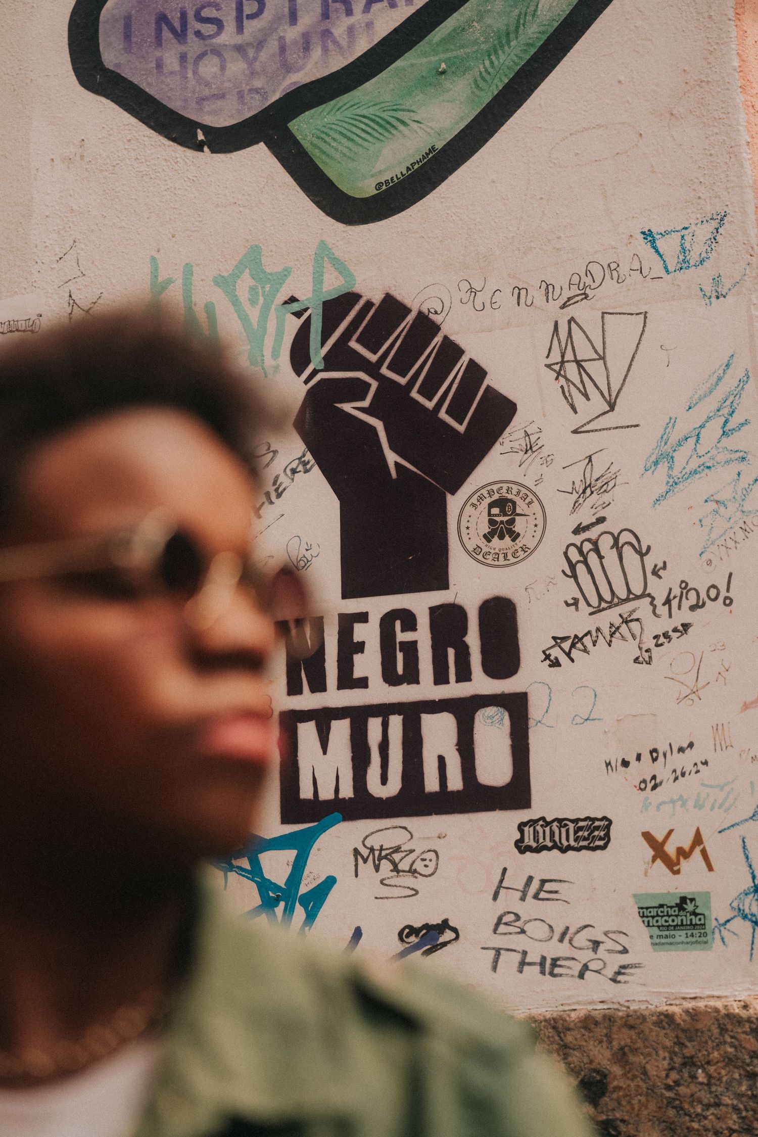 Urban graffiti and street art on a light colored wall featuring black text and various designs.