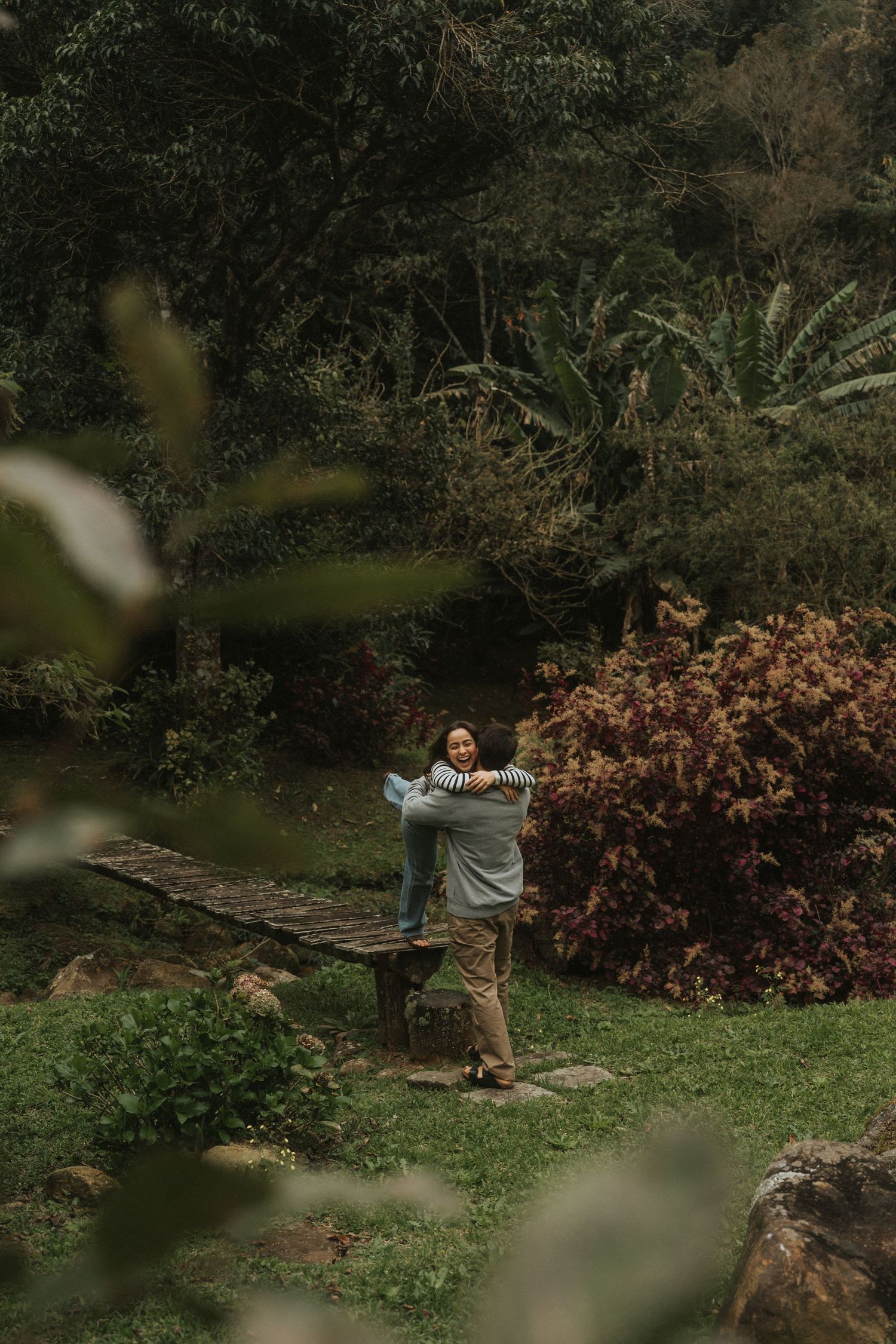Person taking photographs in a lush garden setting with fallen autumn leaves and natural scenery.