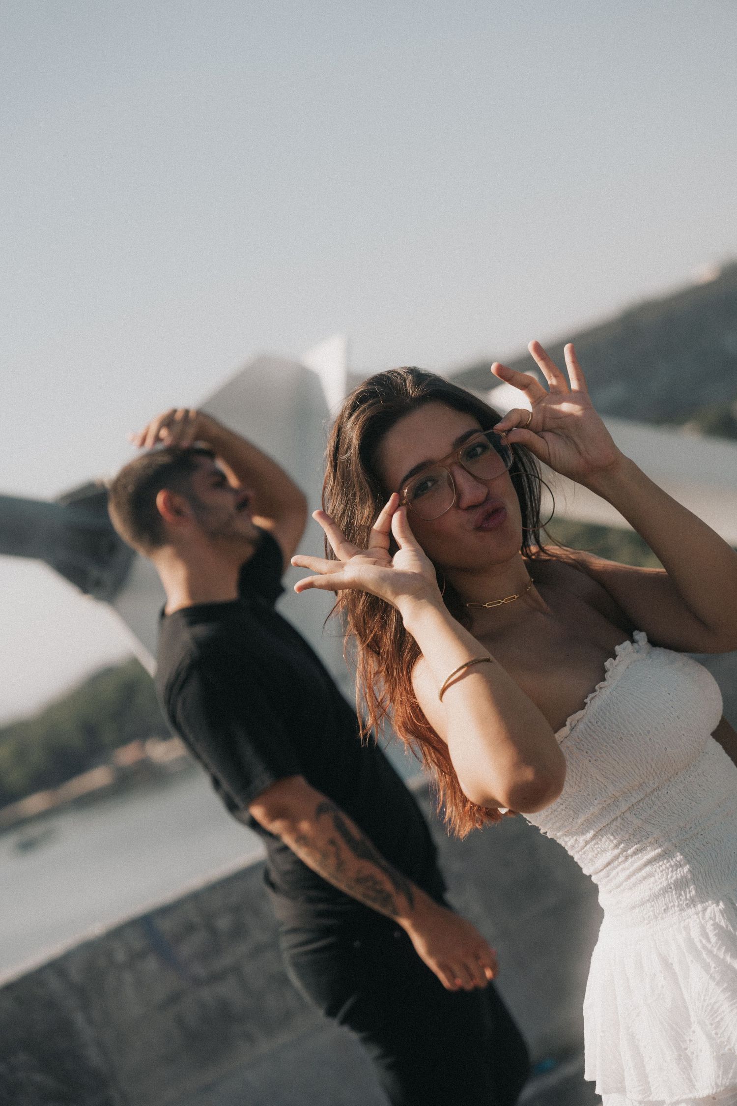 A couple dances together in golden sunlight against a scenic mountain backdrop, creating a romantic moment.