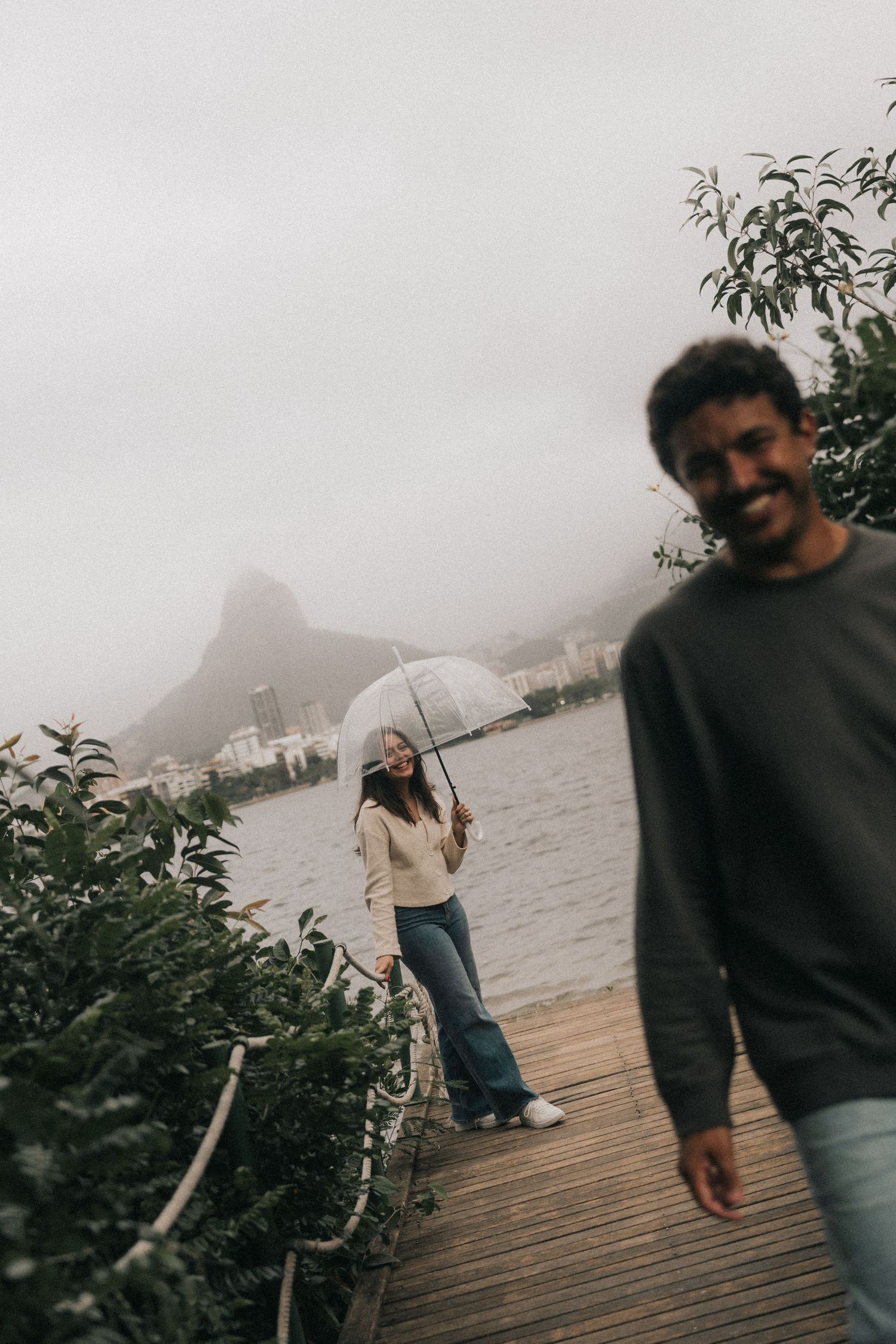 Four connected moody photos of people walking on a wooden dock by the water on a foggy, atmospheric day.