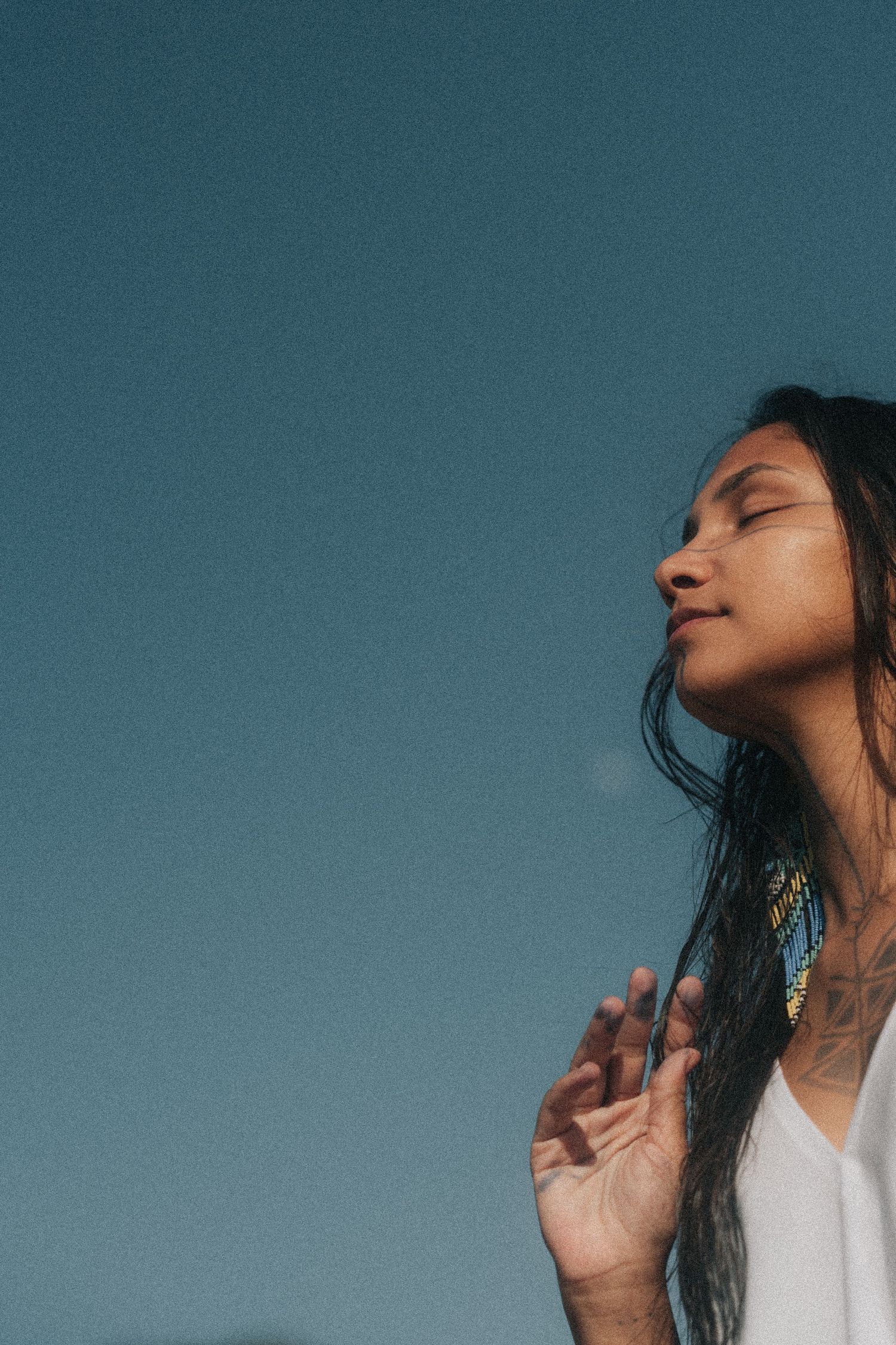 A profile silhouette of a woman with long dark hair leaning back against a teal blue background.