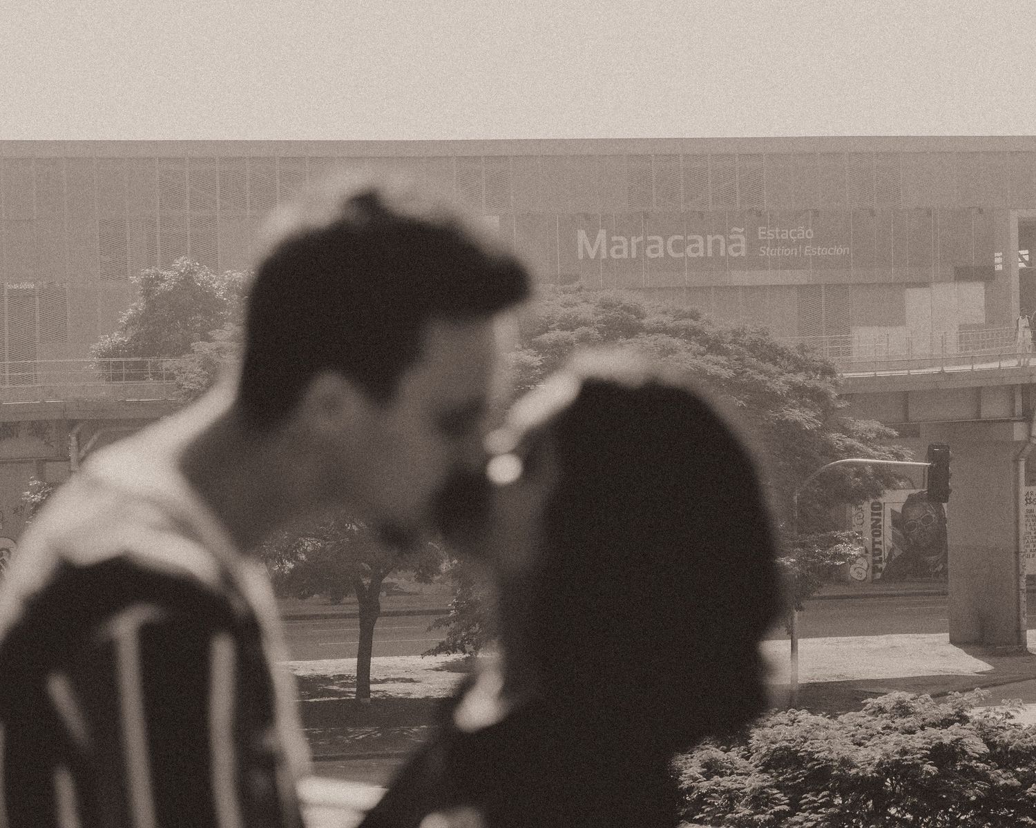 A black and white silhouette of a couple about to kiss with Maracana sign visible in the background.