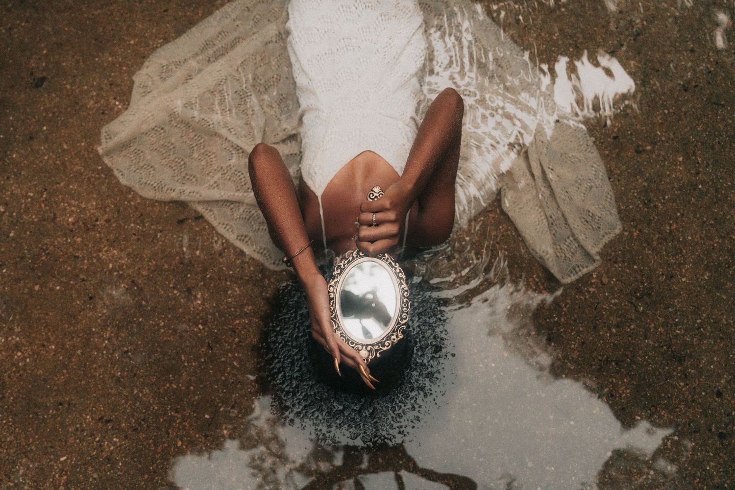 A playful moment captured during a wedding as a bride in a flowing white dress scatters glitter in the sunlight.