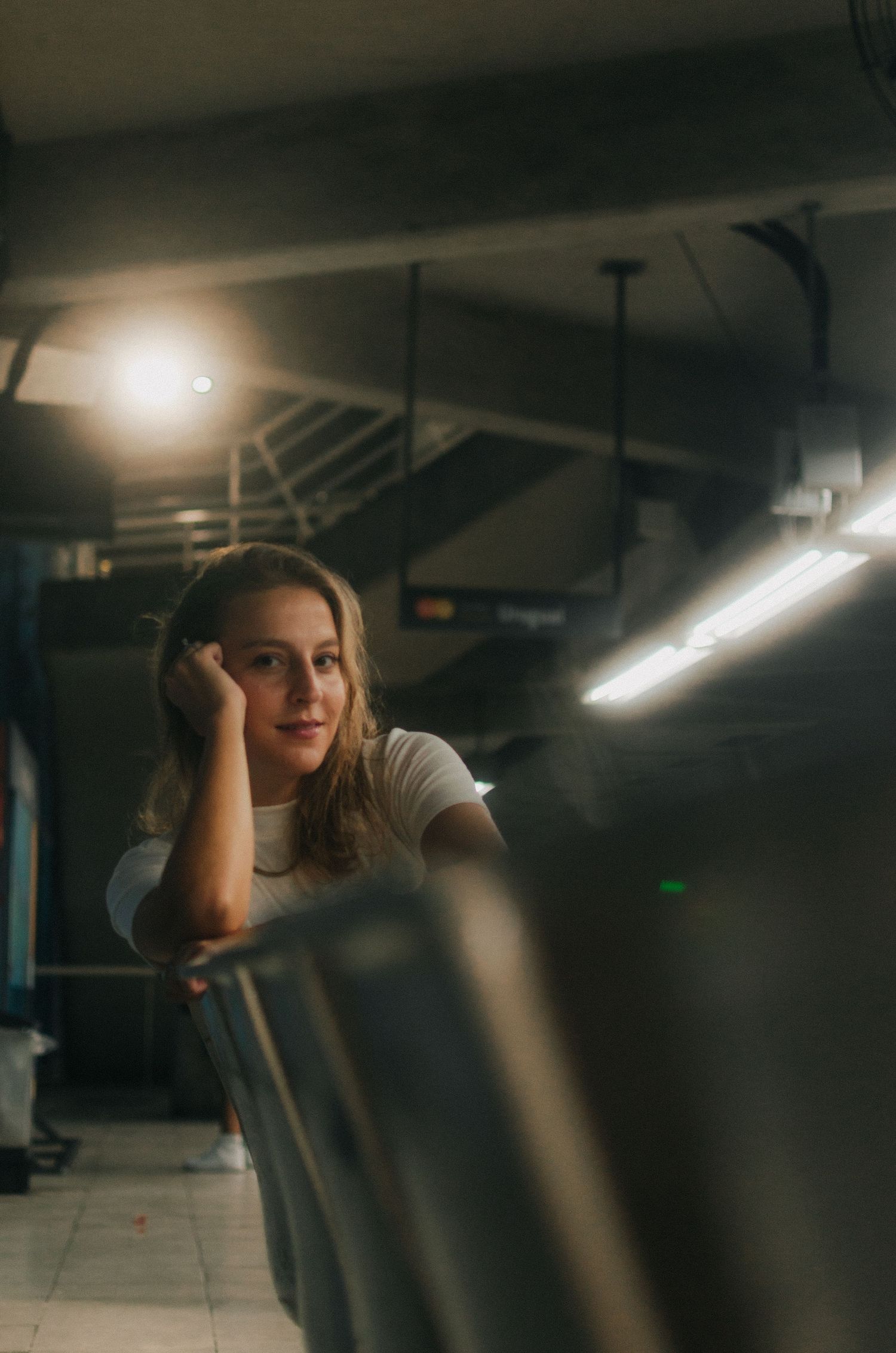 Figure sits in darkened parking garage with dramatic lighting creating a moody cinematic atmosphere.