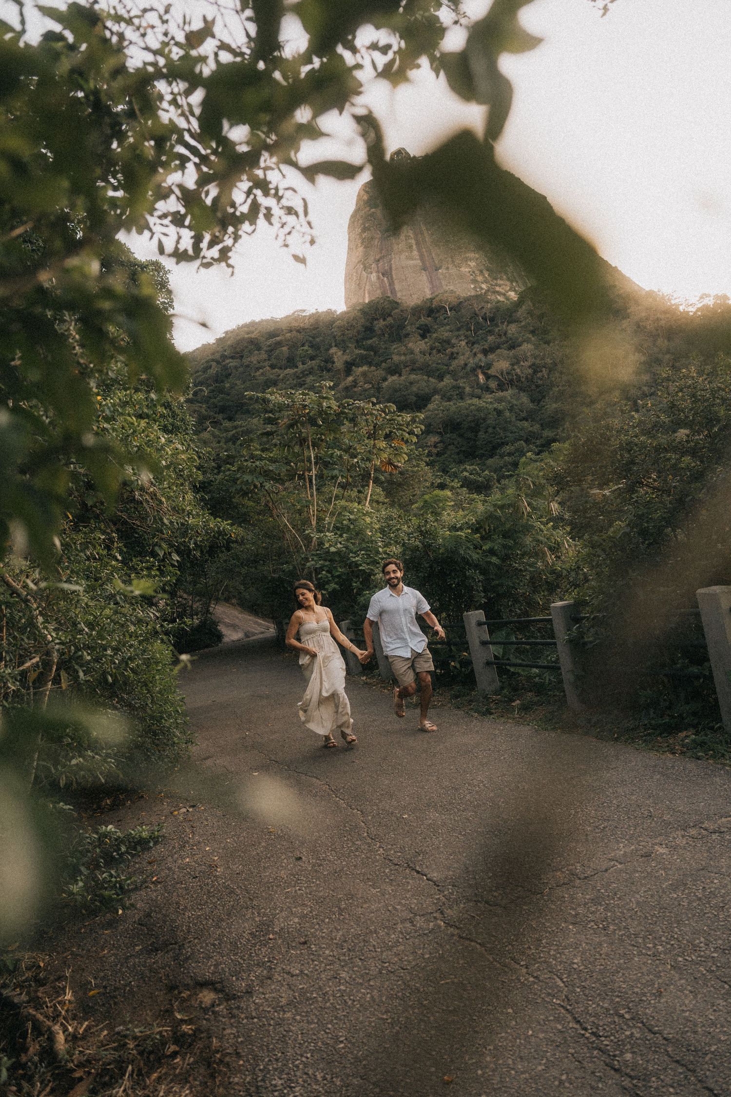 Two people walking together on a wooded trail during golden hour with sunlight filtering through the trees.