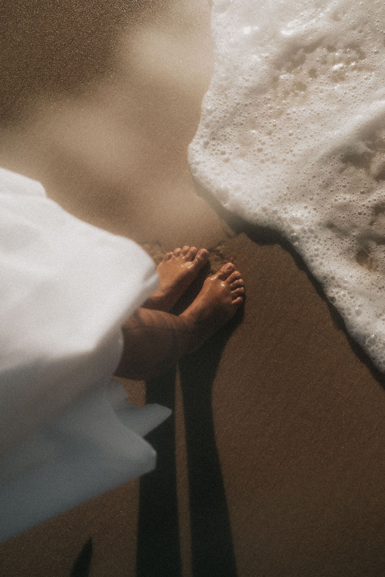 A person's hand hiding under a white blanket or duvet cover in a series of progressive shots.