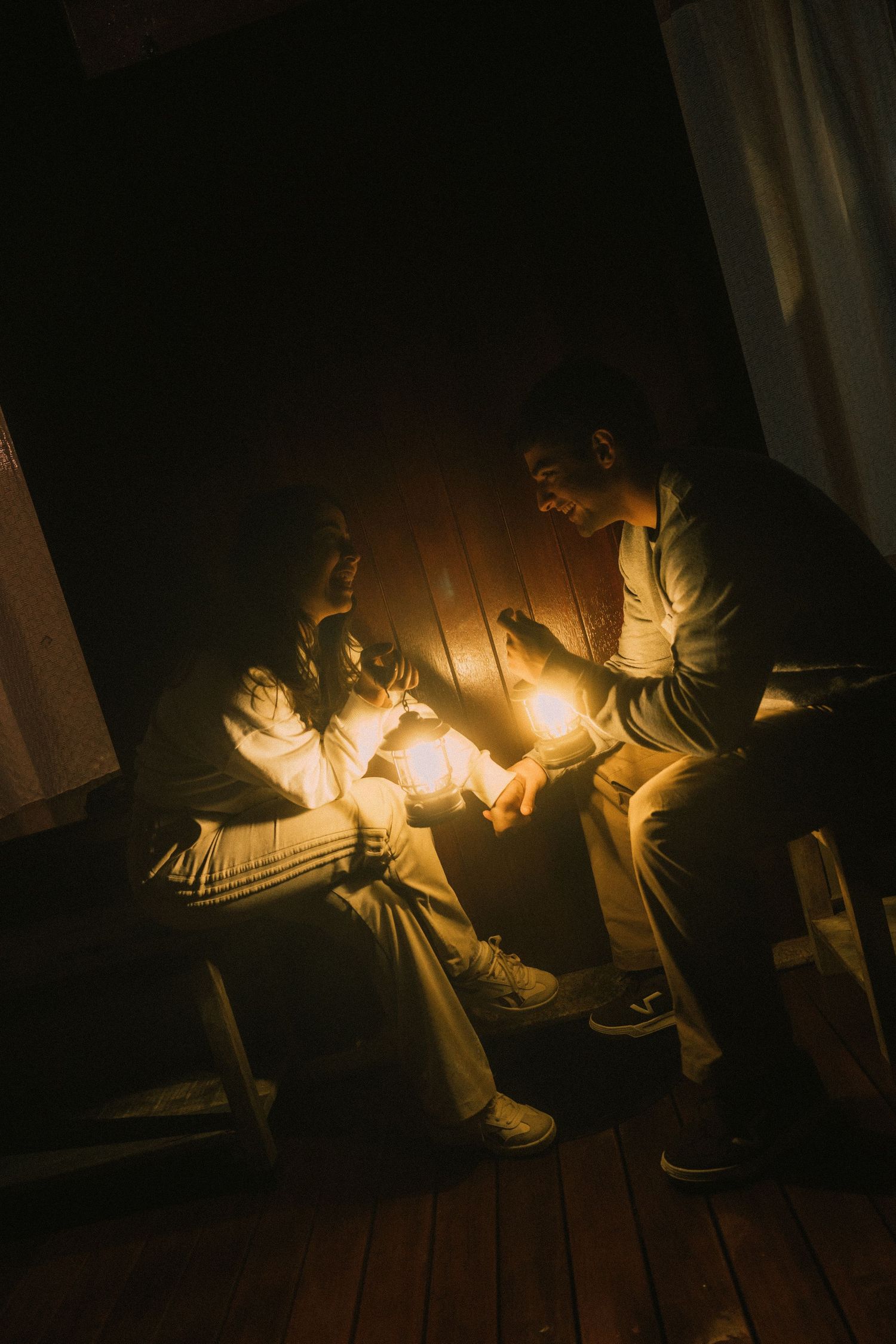 A sequence of dimly lit photos showing someone sitting on wooden floor reading by flashlight in dark room.