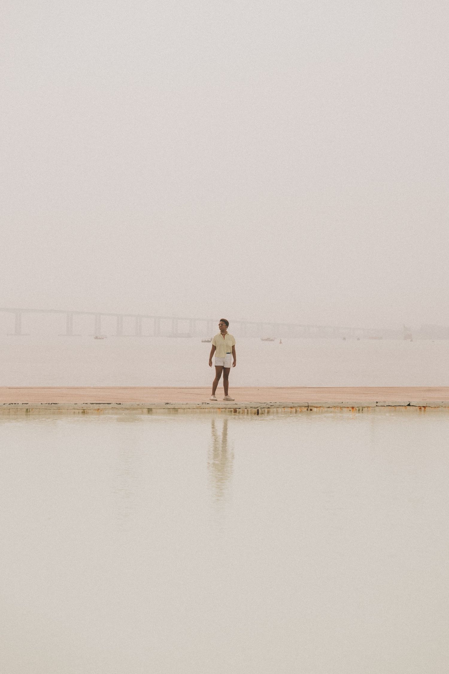 A lone figure stands on a minimalist salt flat landscape creating a serene and ethereal scene in muted tones.
