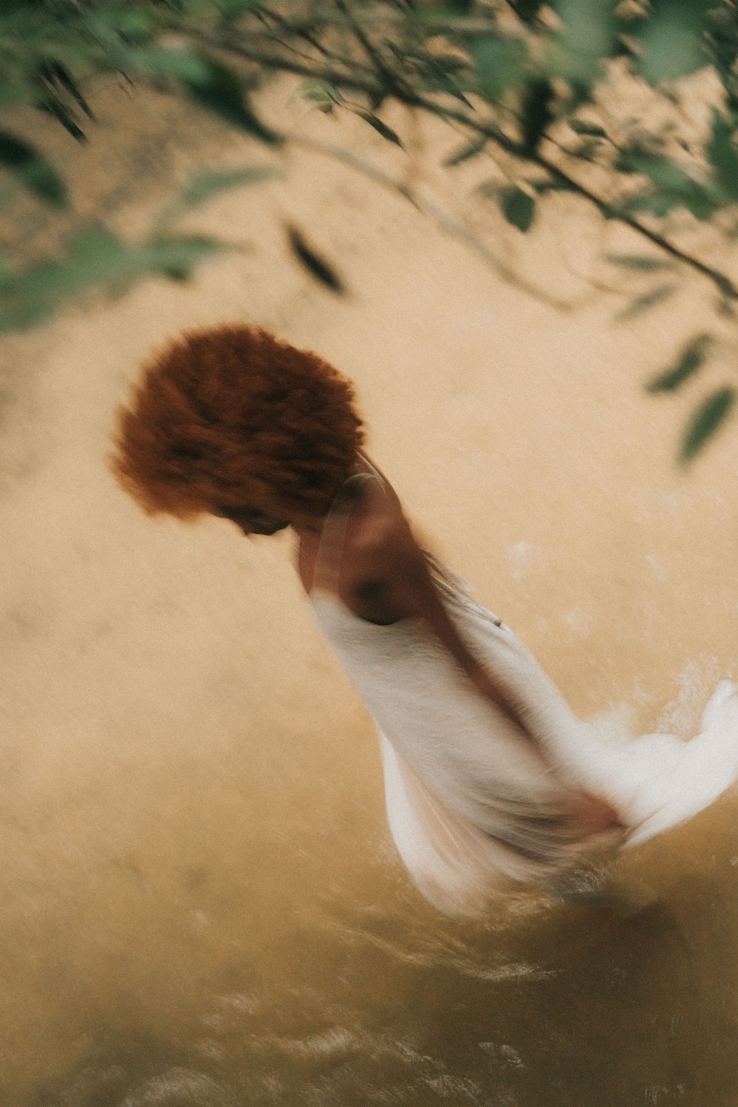 A sequence of motion-blurred photographs showing a white dress swirling against a beige background with olive leaves above.